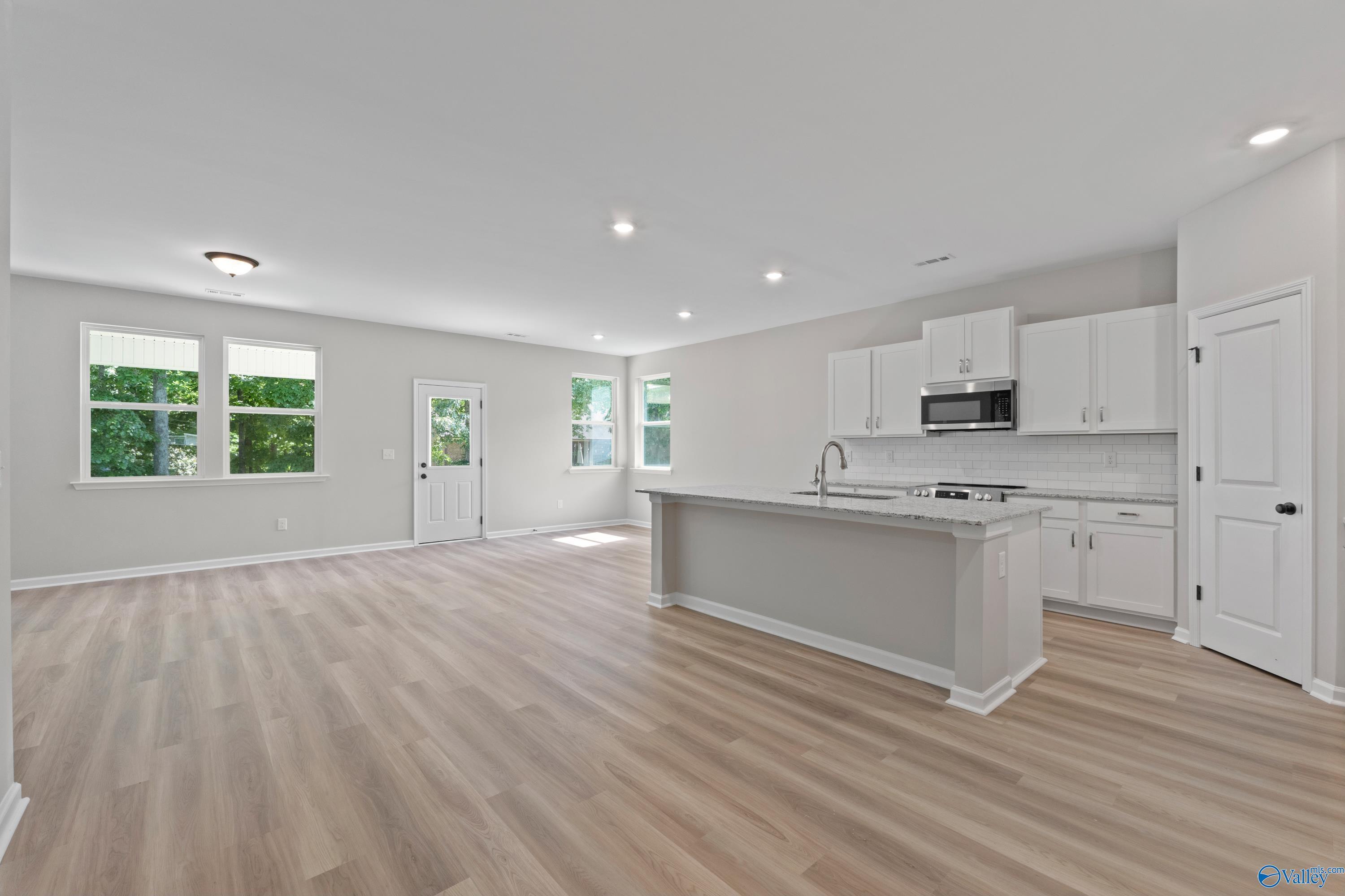 Open-concept kitchen with white cabinets, stainless appliances, and large island in Davidson Homes The Phoenix, Fayetteville, TN
