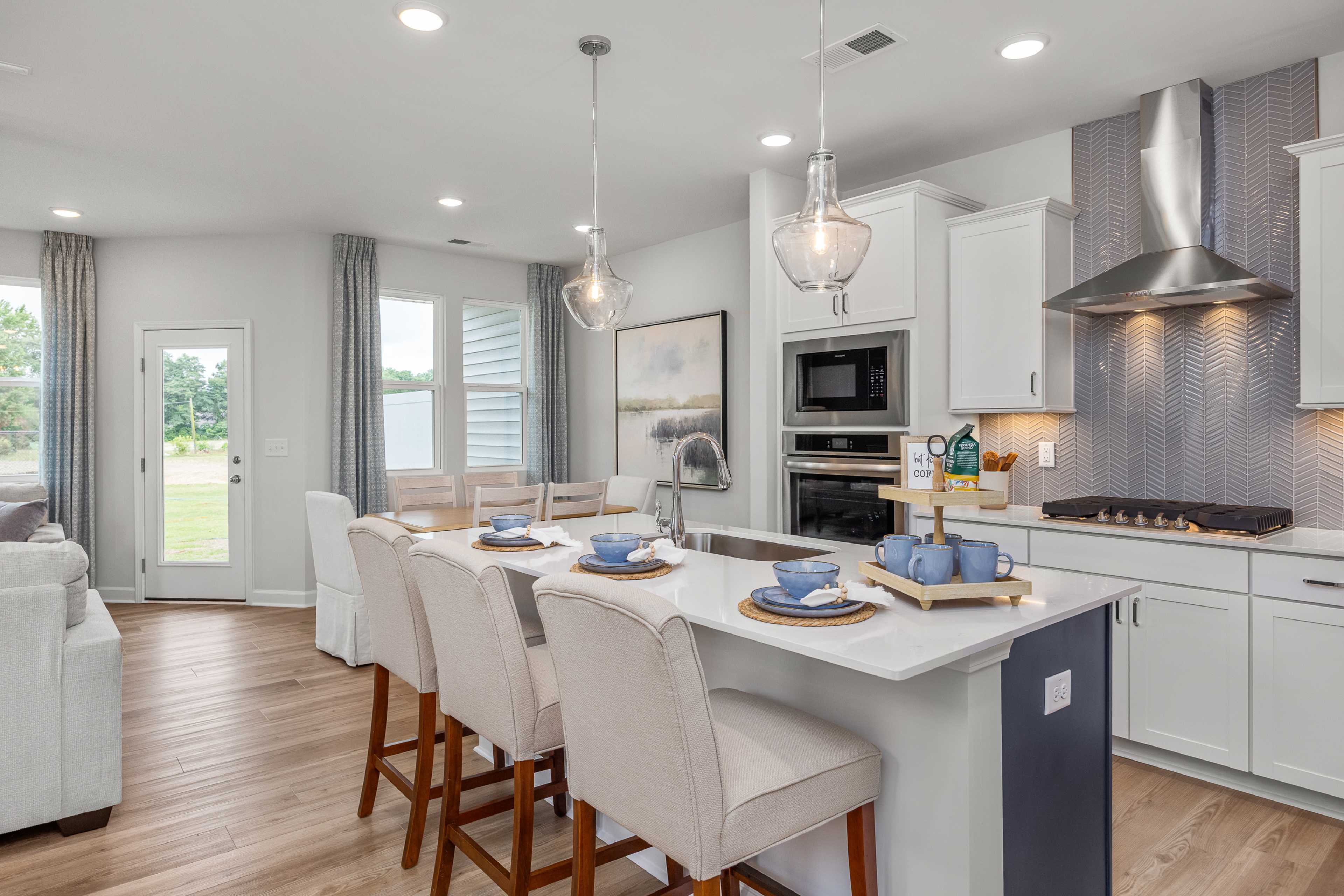 Modern kitchen in Springvale, Fuquay-Varina NC with white shaker cabinets, stainless appliances, subway tile backsplash, and large center island