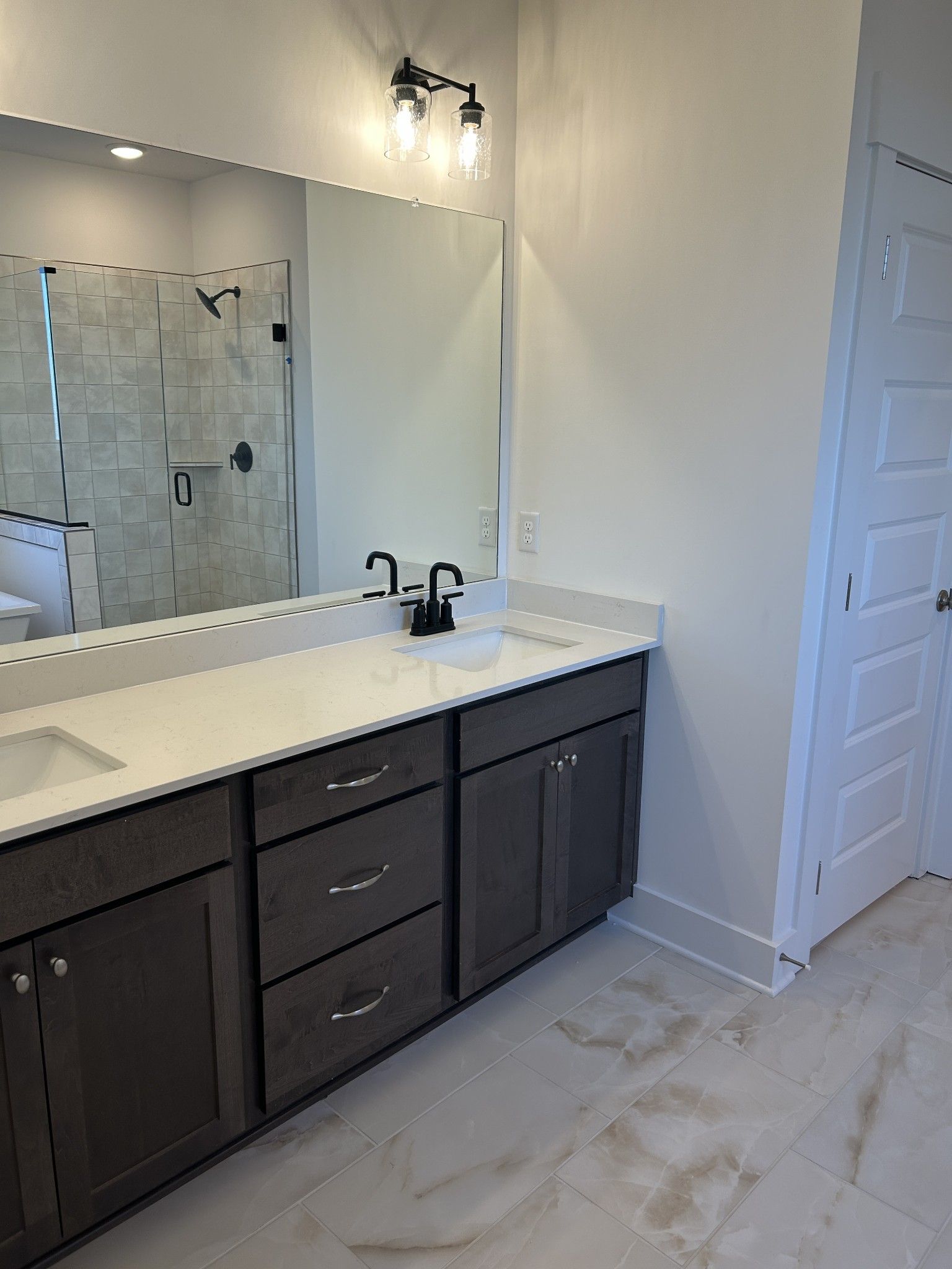 Modern master bathroom featuring double vanity with quartz countertop, dark cabinets, frameless glass shower in Davidson Homes Ridgeport F, Mt. Juliet