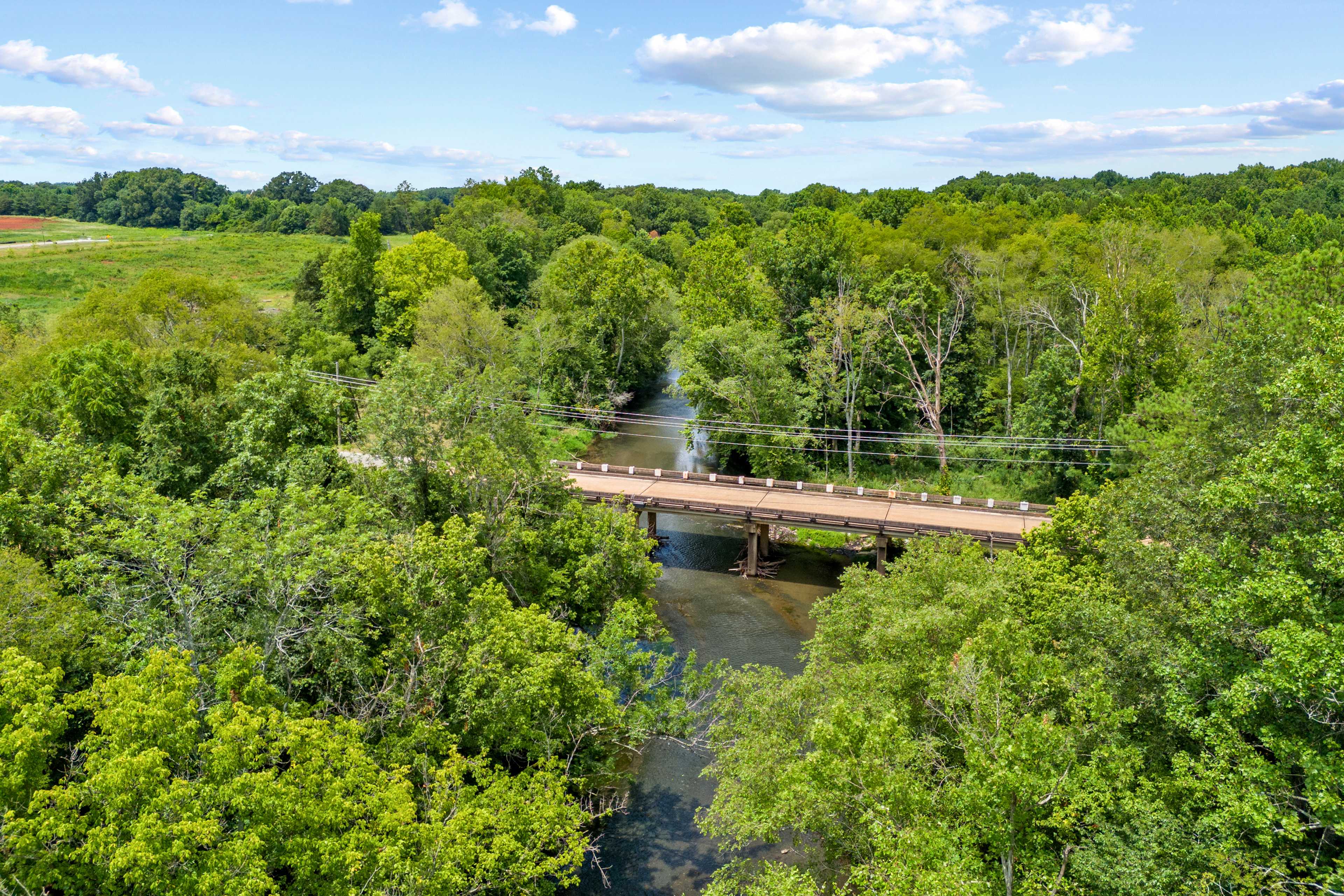 Scenic wooden bridge over creek at The Meadows in Athens Alabama amid lush green forests and fields