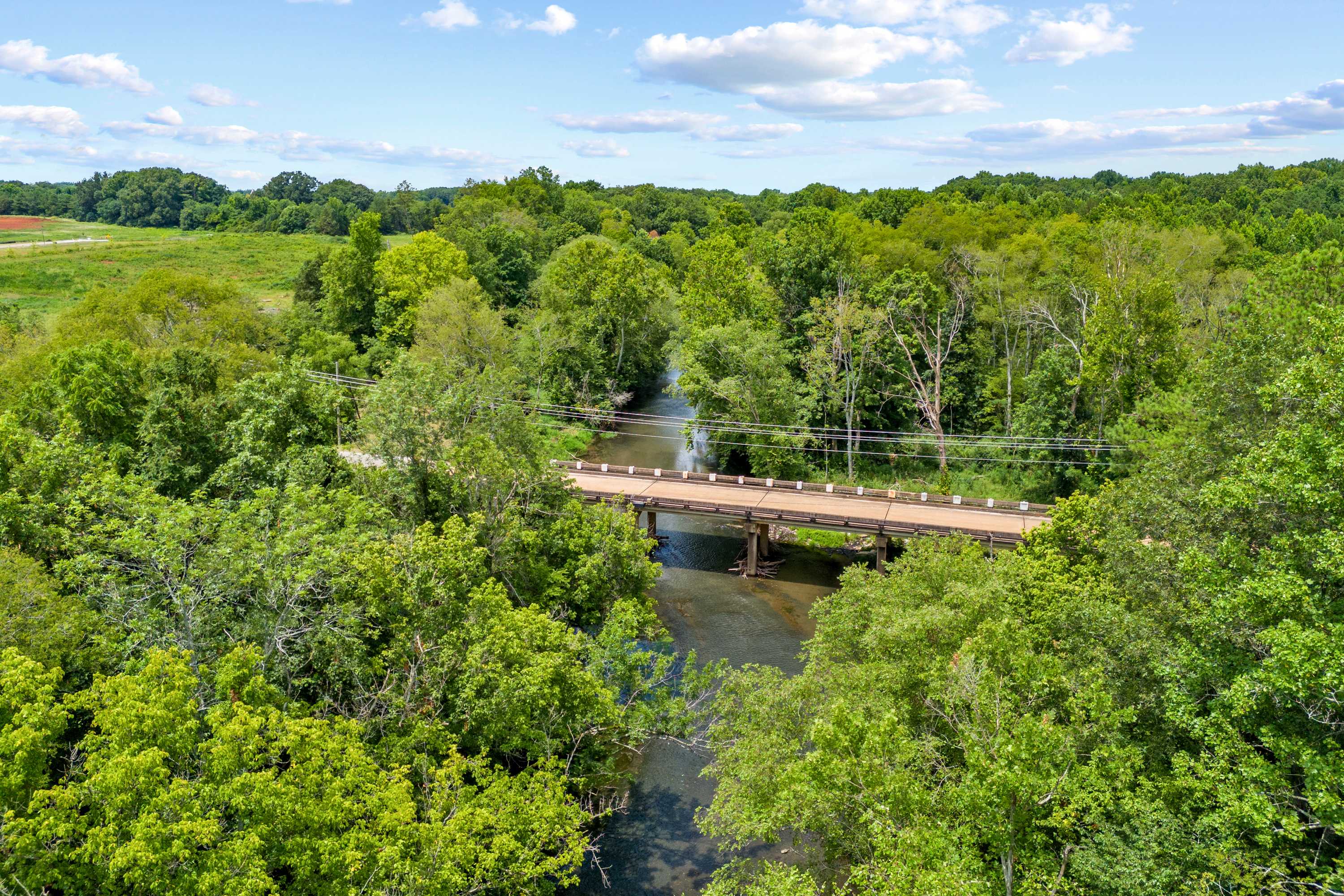 Scenic wooden bridge over creek at The Meadows in Athens Alabama amid lush green forests and fields