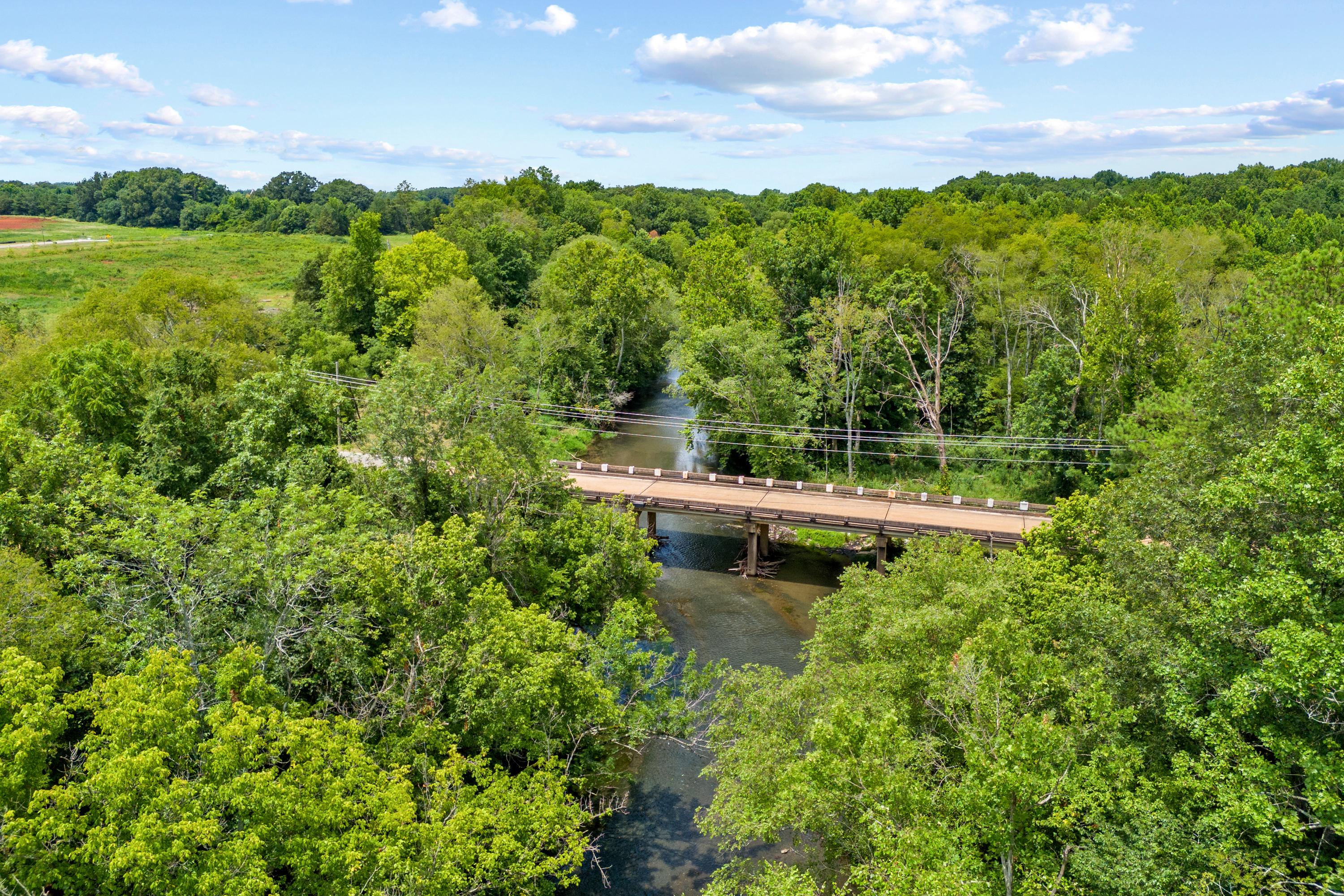 Scenic wooden bridge over creek at The Meadows in Athens Alabama amid lush green forests and fields