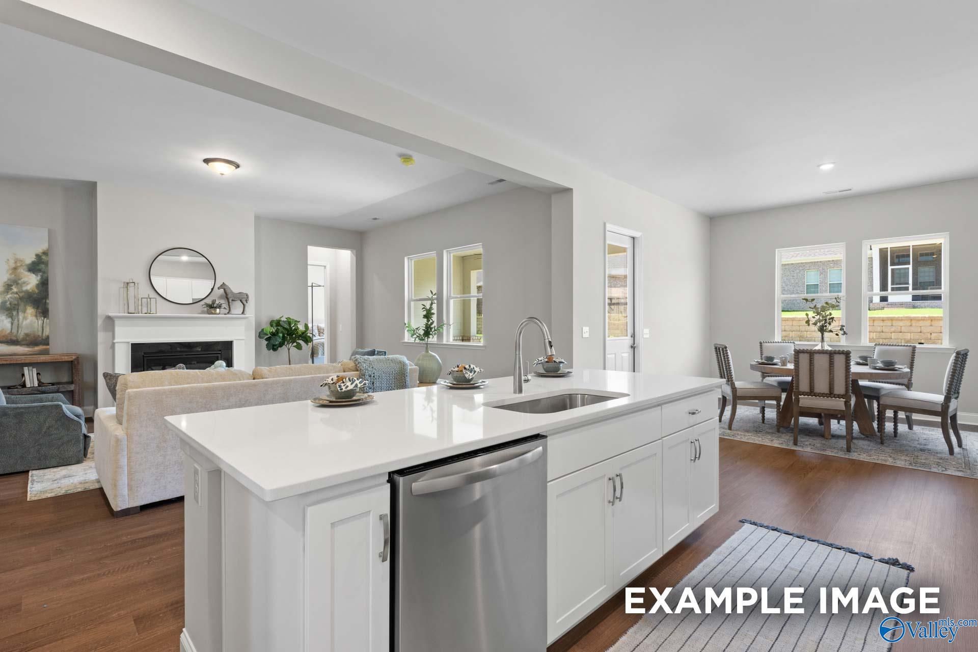 Open-concept kitchen with white island, stainless dishwasher, and adjacent living-dining area in Evermore Homes The Haven E, Owens Cross Roads, AL
