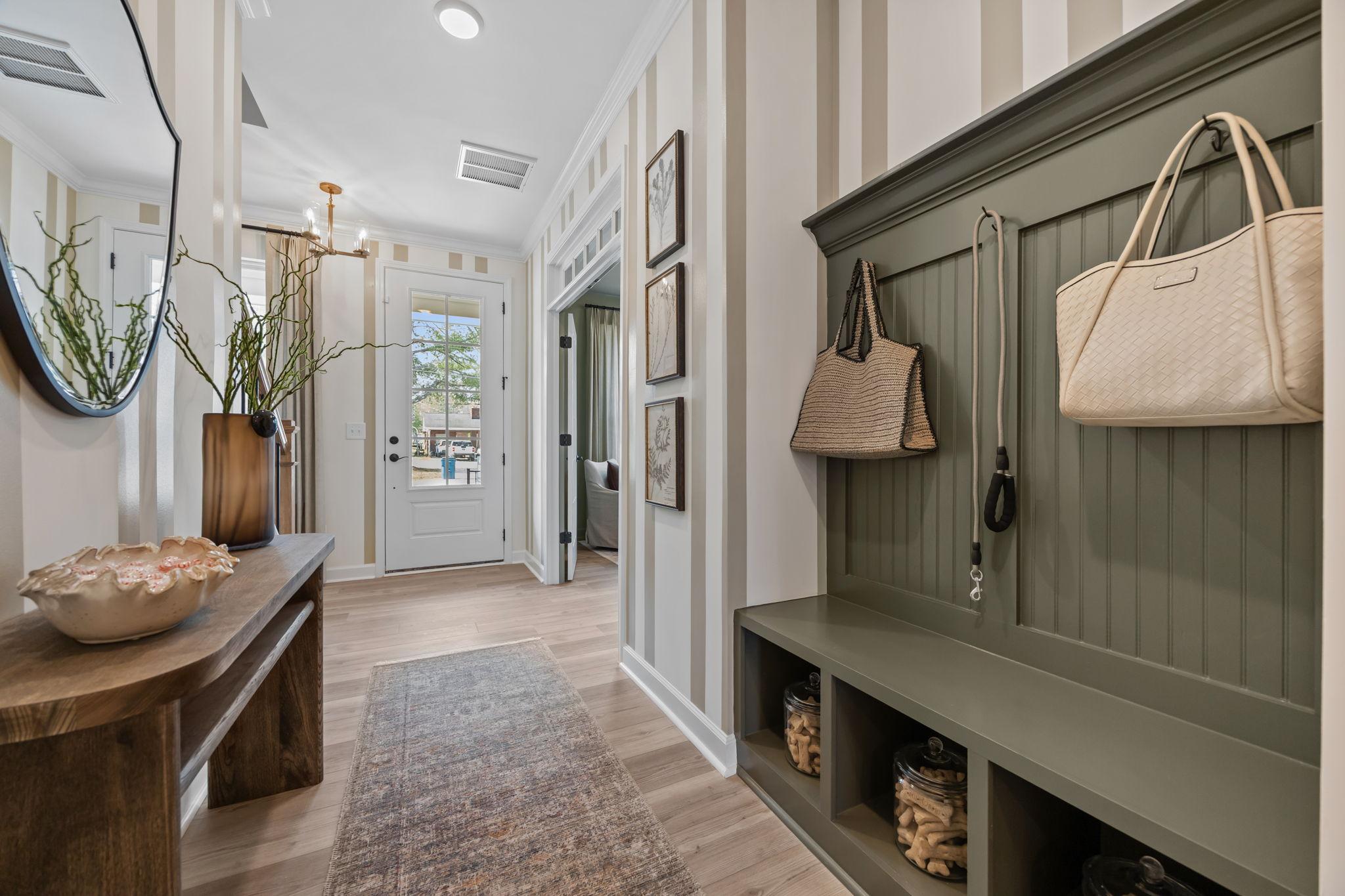 Spacious entryway in Camden Park Knightdale NC home with green shiplap bench, coat hooks, potted plants, and pool view