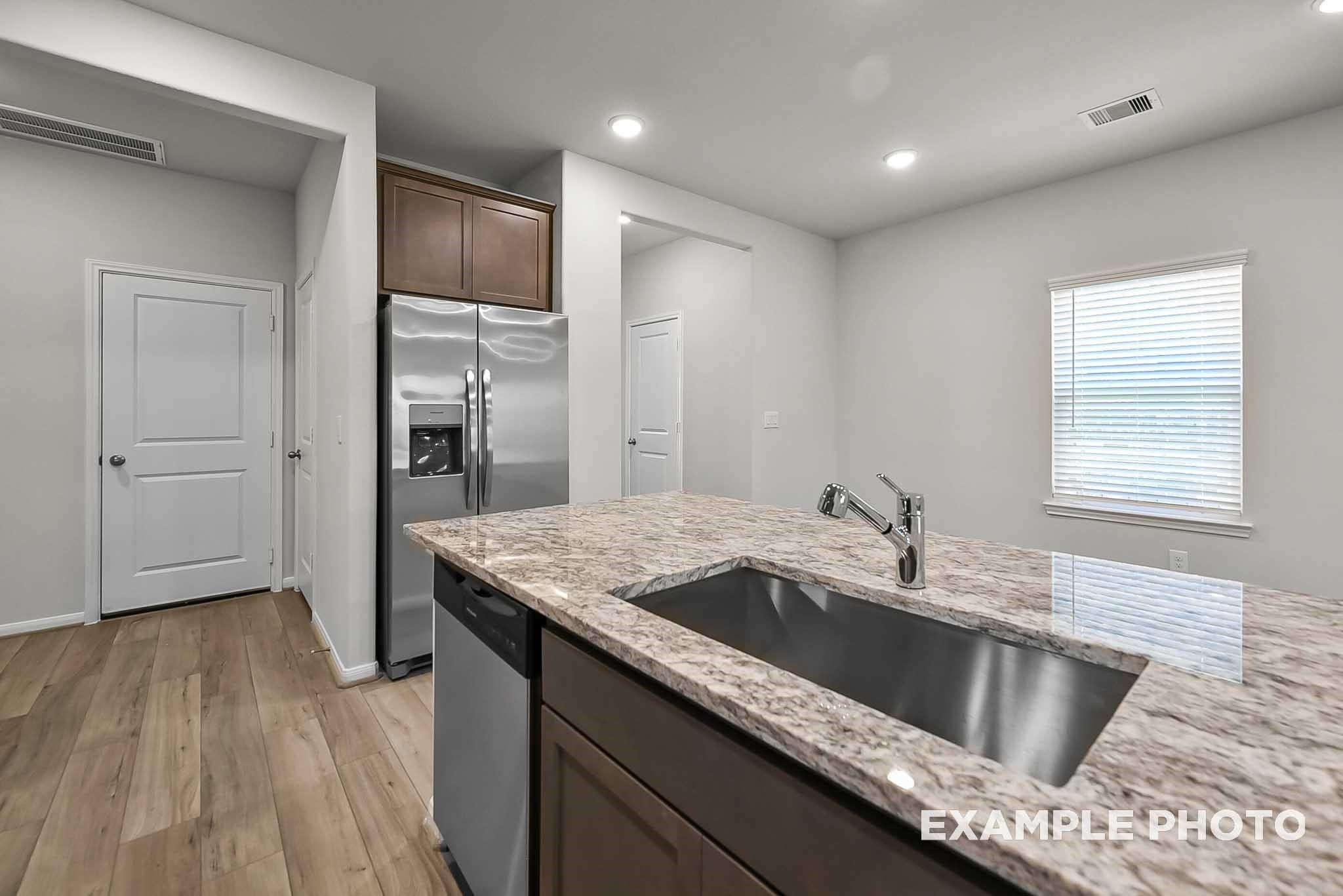 Modern kitchen island with granite countertop and stainless steel sink in The Blanco F plan at Spring Branch Crossing.