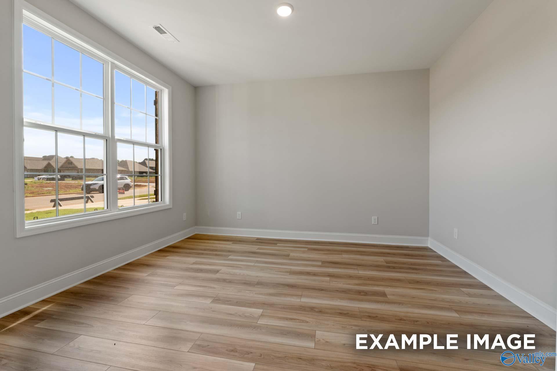 Bright empty bedroom with large windows and hardwood floors in 5-bedroom Davidson Homes The Madison A, Toney, Alabama