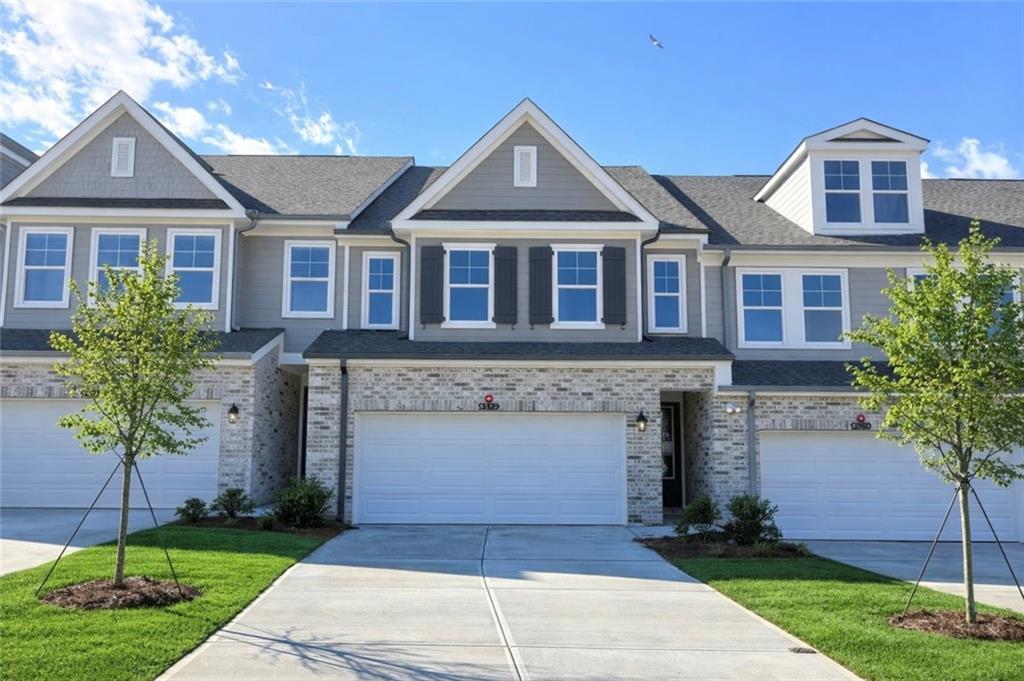Modern 2-story townhomes with gray siding, brick accents, garages, and landscaped driveways in Hemingway, Cumming, Georgia
