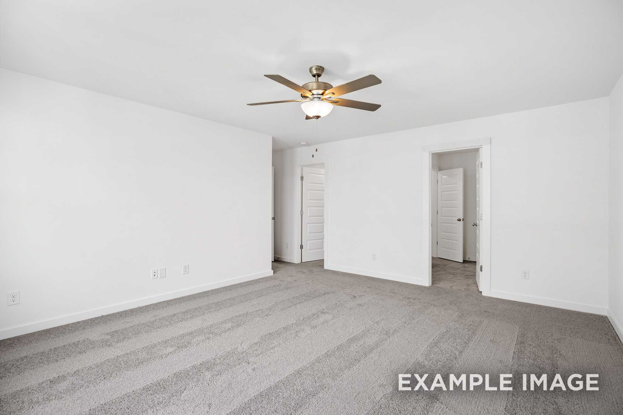 Spacious empty master bedroom in The Murray B featuring gray carpet, white walls, ceiling fan, and adjacent bath doorway