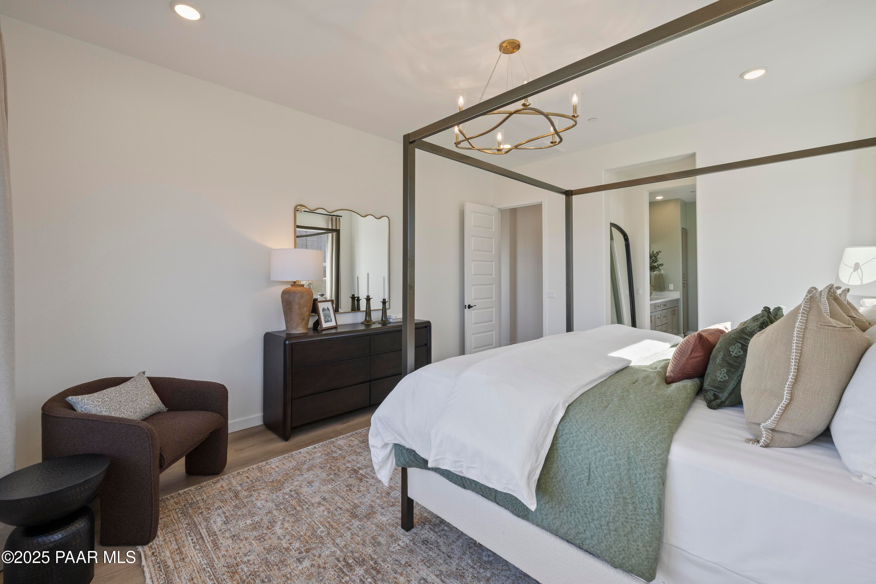 Elegant master bedroom with four-poster bed, chandelier, dresser and en-suite bath in Davidson Homes The Blaze D, Prescott Arizona