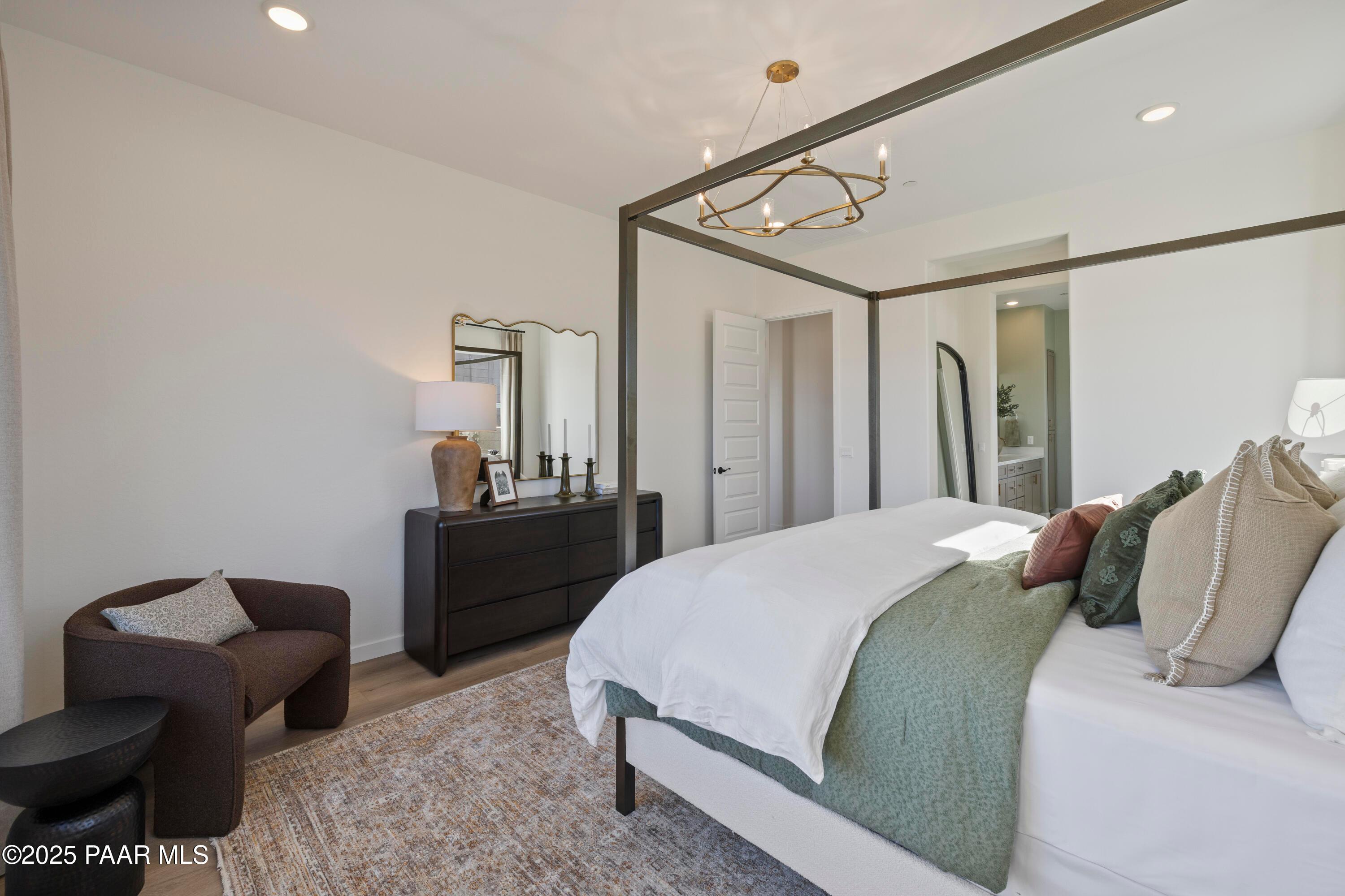 Elegant master bedroom with four-poster bed, chandelier, dresser and en-suite bath in Davidson Homes The Blaze D, Prescott Arizona