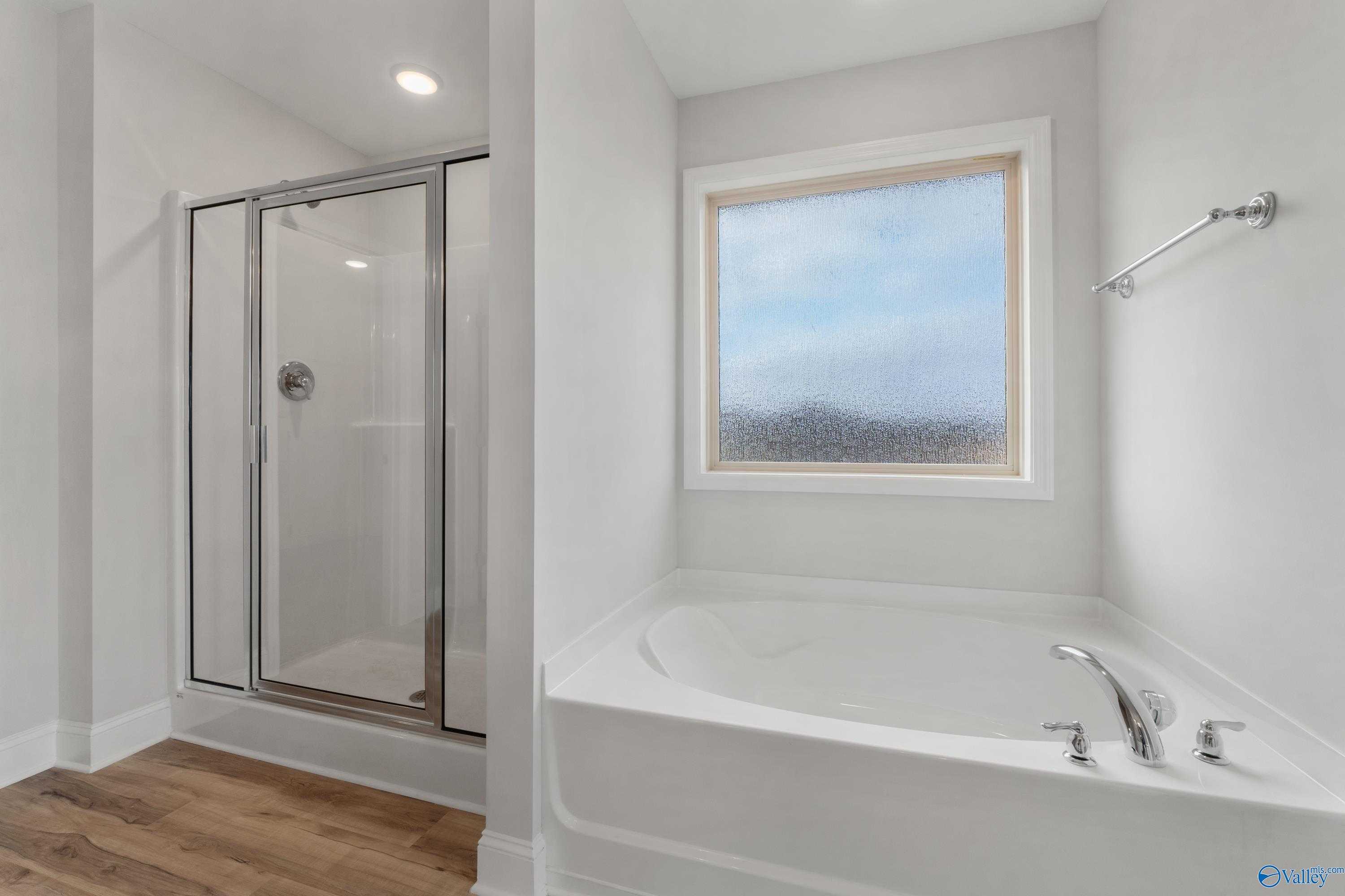 Modern master bathroom featuring frameless glass shower and soaking tub in Davidson Homes Chelsea C, Harvest, Alabama