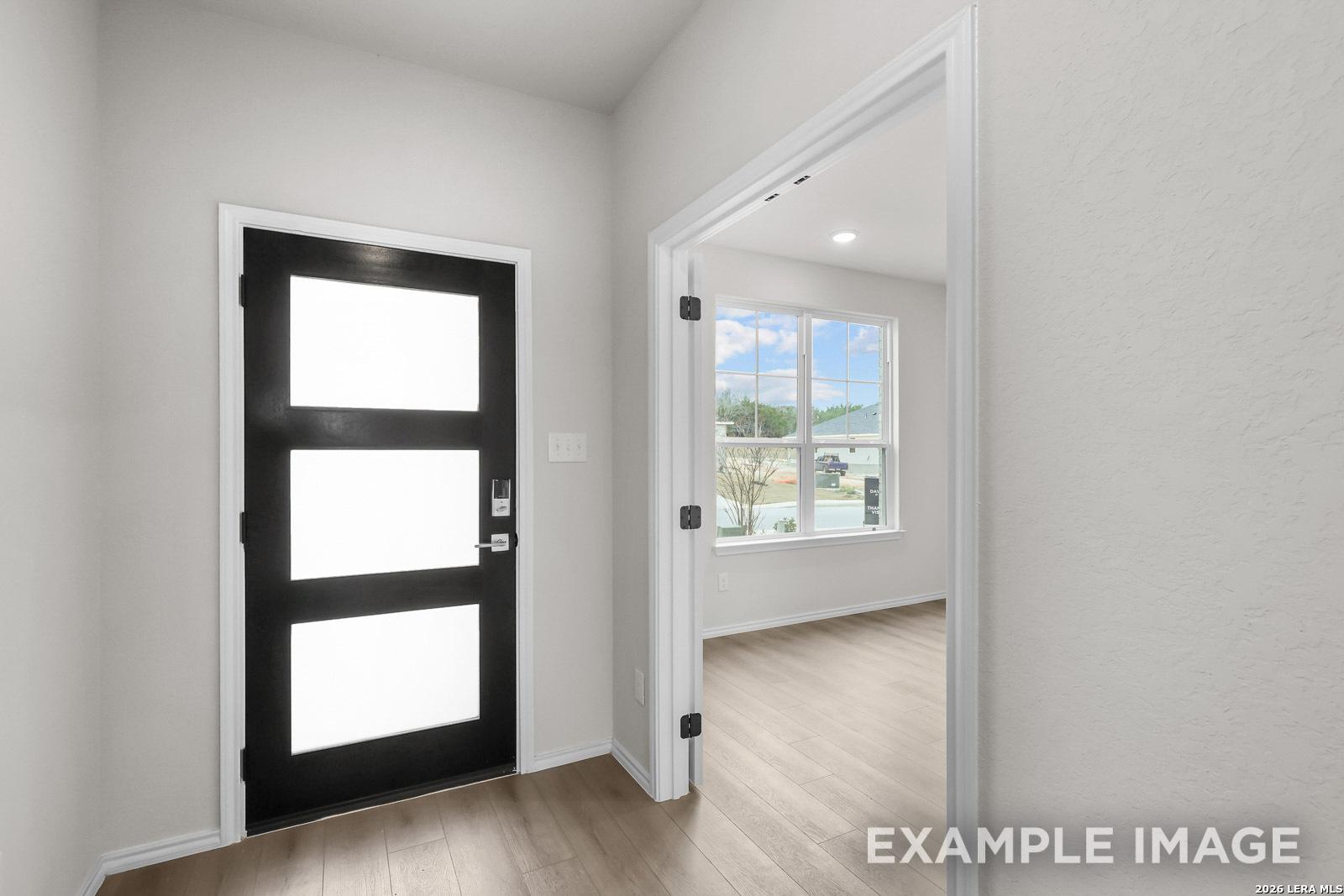 Modern black front door and entryway leading to a bright room in The Sequoia C floor plan by Davidson Homes in San Antonio.