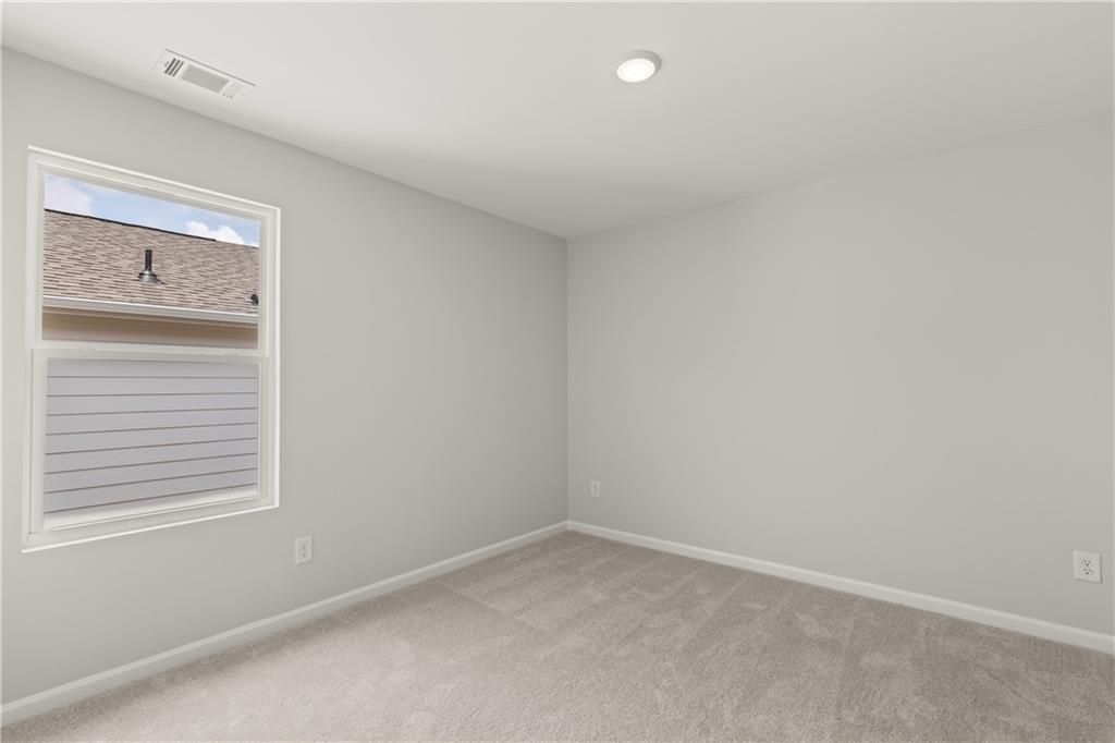 Bright, neutral-toned bedroom with plush carpeting in The Hartwell A floor plan at The Bluffs in Canton, Georgia.