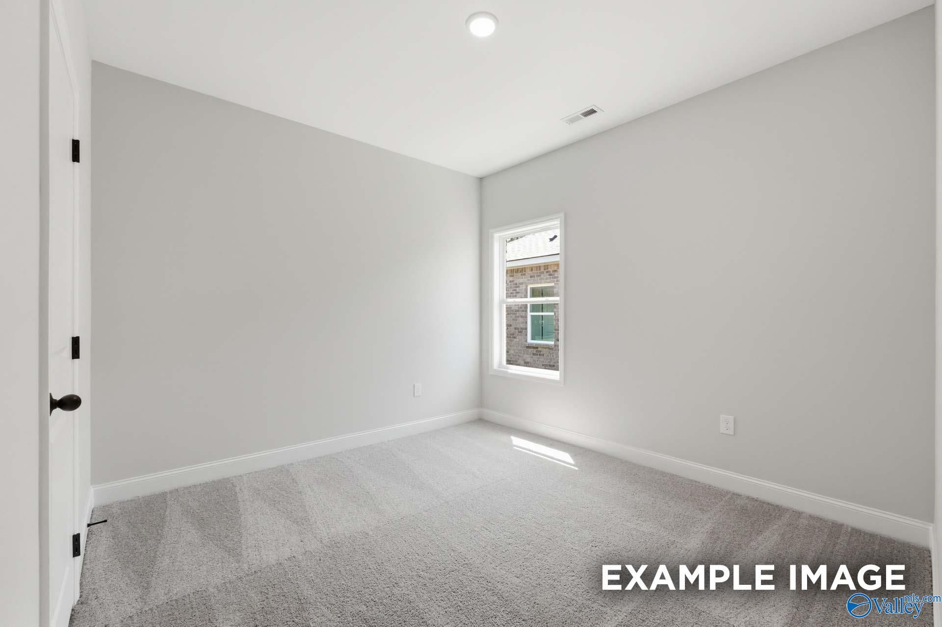 Bright, spacious secondary bedroom with neutral carpet and walls in The Franklin C floor plan at The Highlands in Arab, AL.