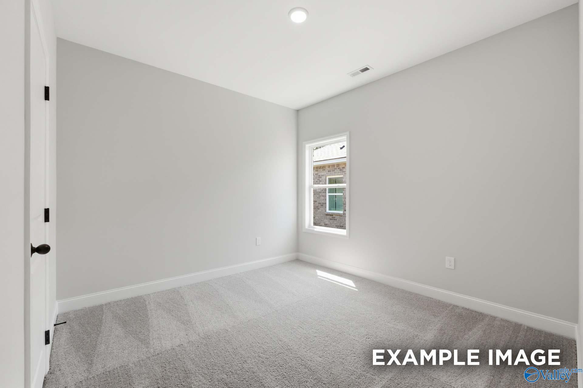 Bright, spacious secondary bedroom with neutral carpet and walls in The Franklin C floor plan at The Highlands in Arab, AL.