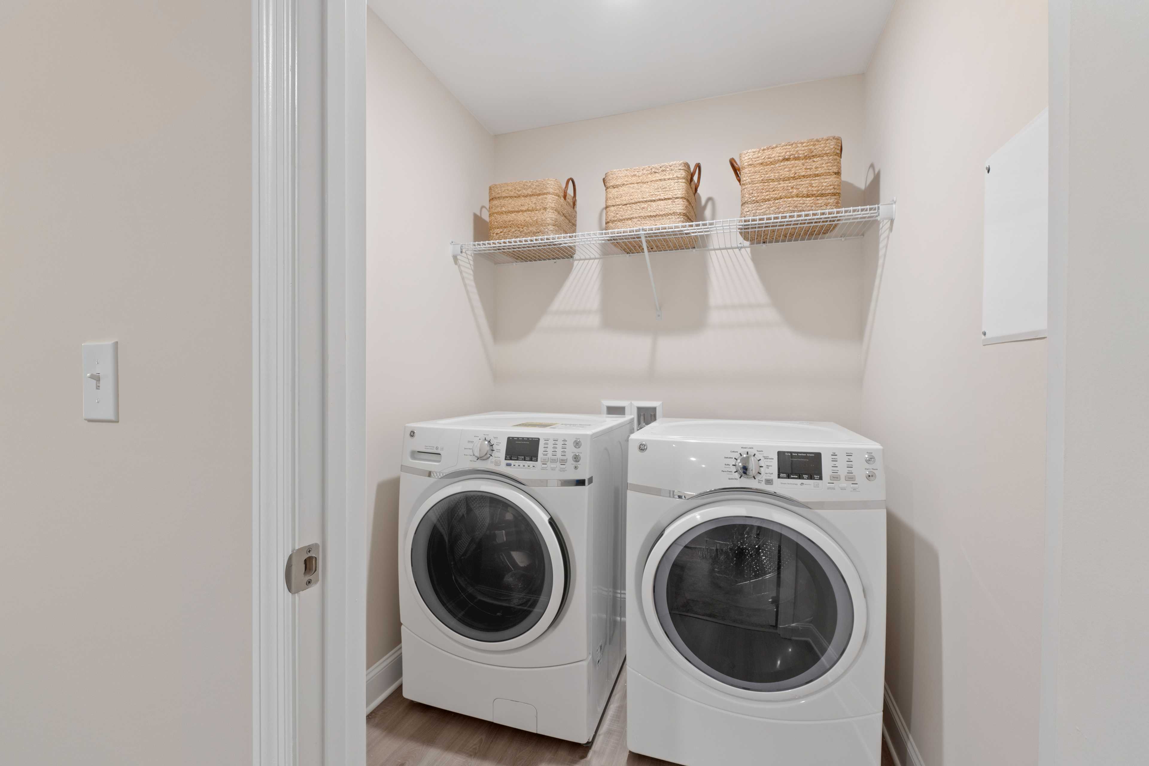 Spacious laundry room in Pavilion Huntsville AL with white front-load washers dryers and wicker basket shelves