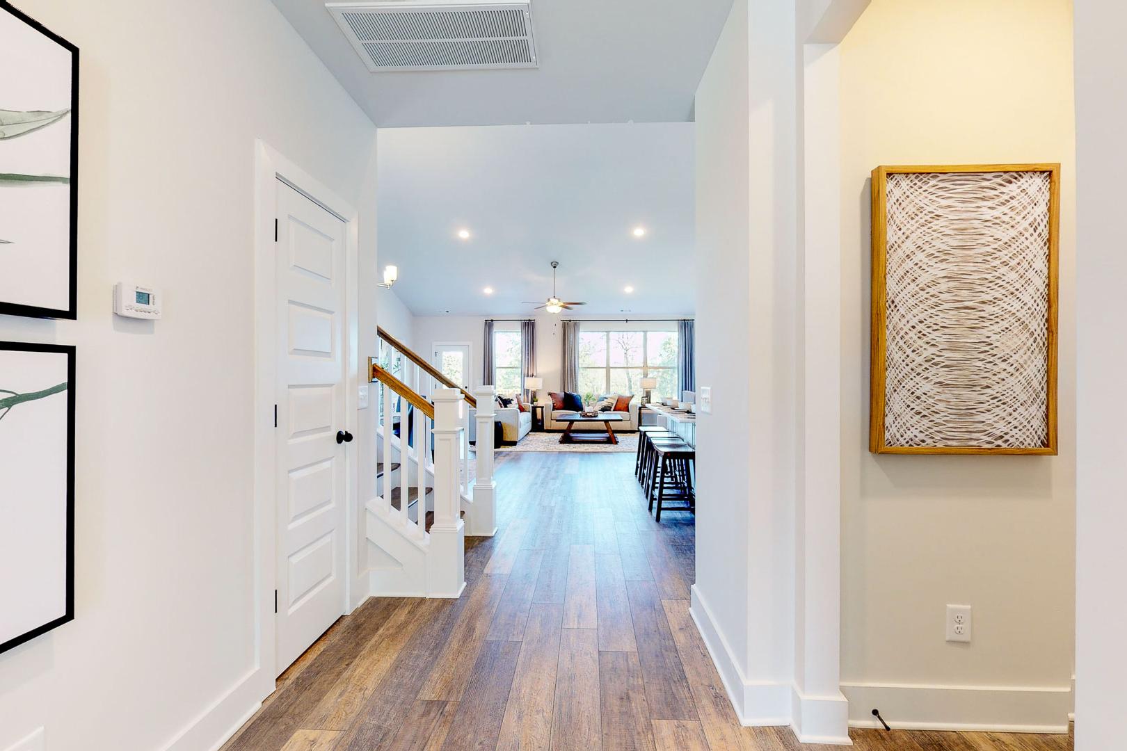 Spacious open-concept hallway in Liberty Creek home, Gallatin TN with hardwood floors, white staircase, and modern wall art