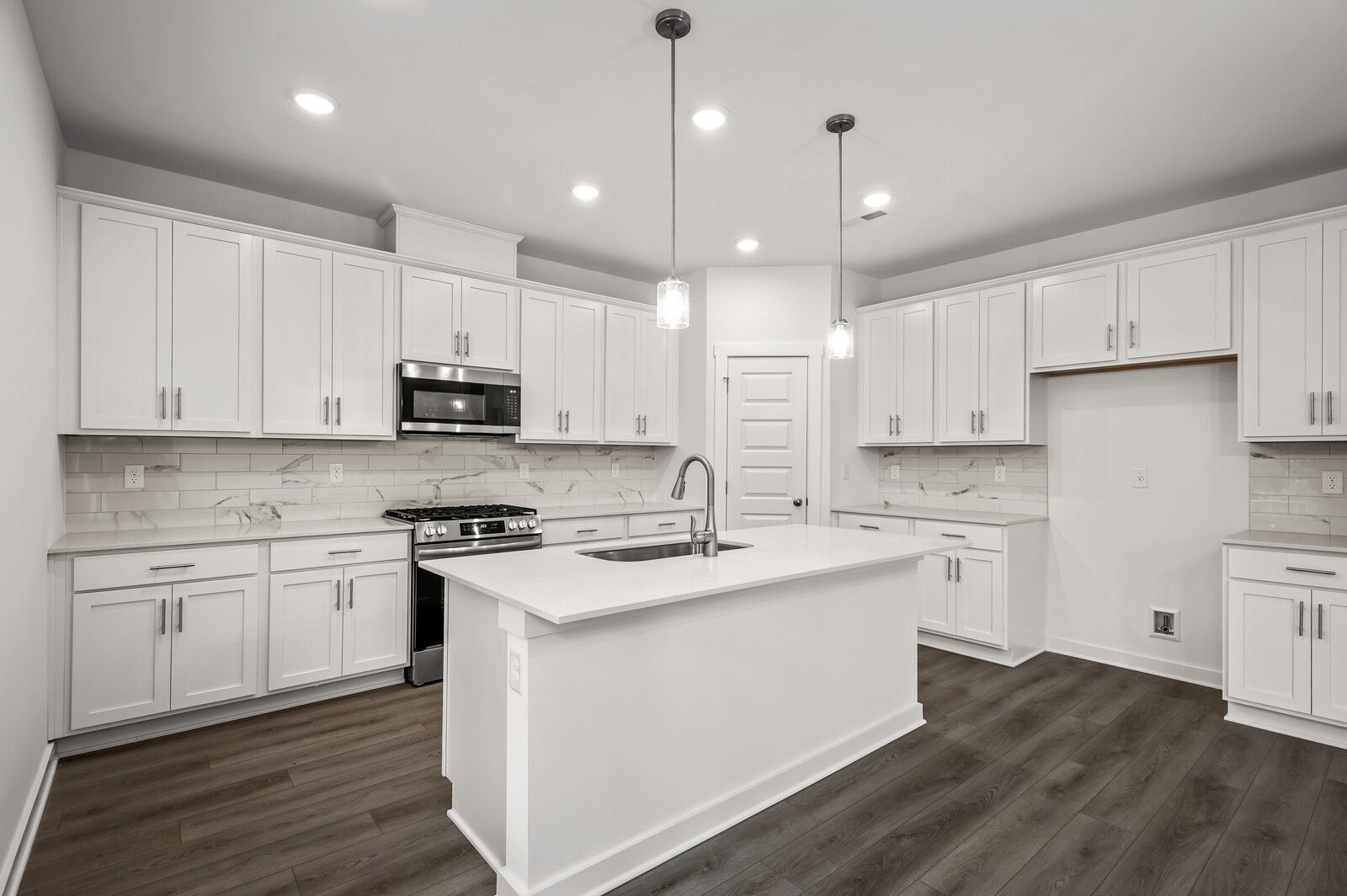 Modern kitchen with white cabinets, quartz countertops, and center island in The Logan C floor plan at Calista Farms.