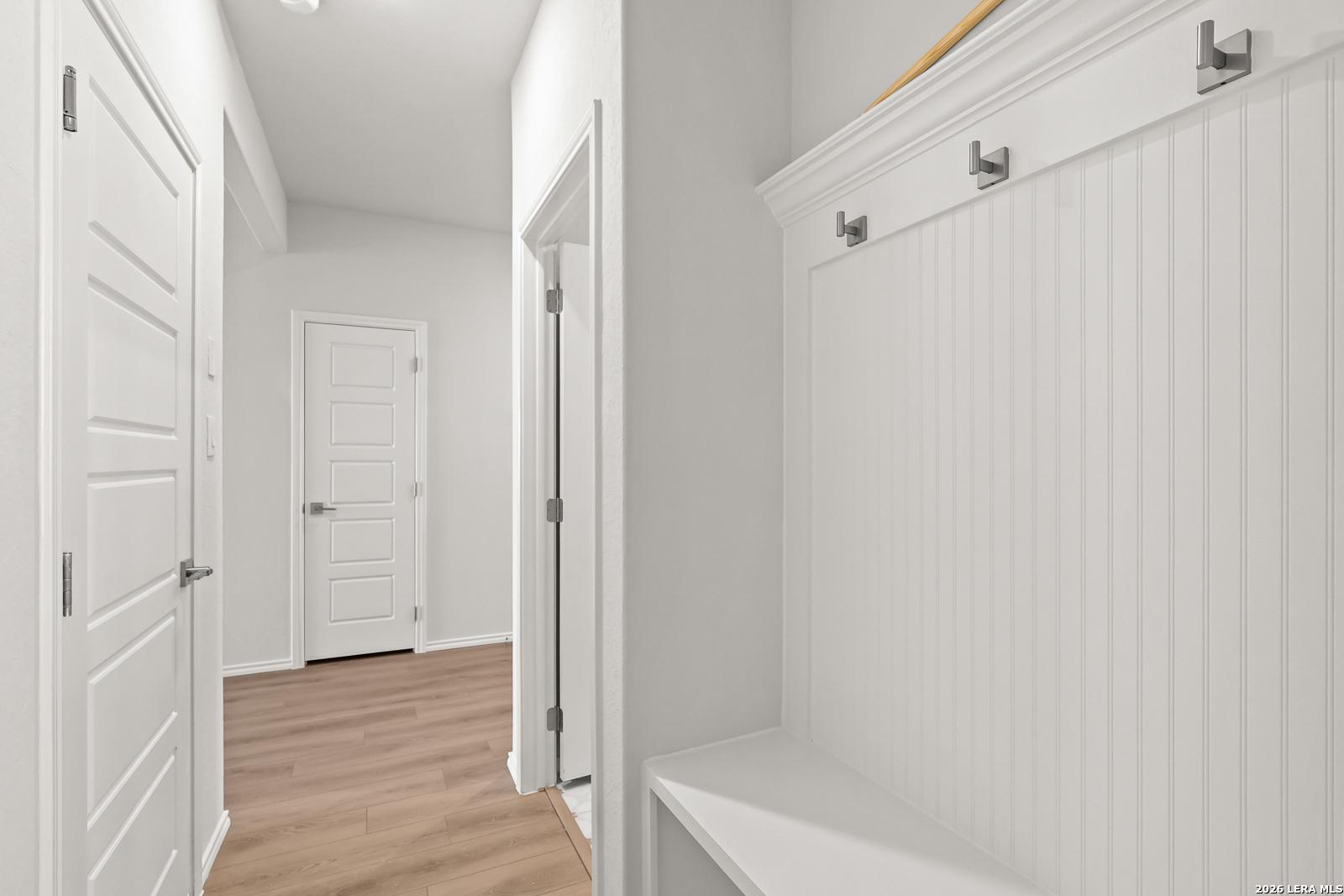 Mudroom with beadboard wall hooks, bench, and hardwood flooring in Davidson Homes The Daphne I, Bricewood, San Antonio, Texas