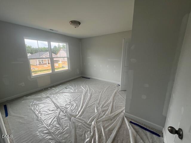 Unfinished bedroom with protective floor covering in The Ash B floor plan at Retreat at North Main, Lillington, NC.