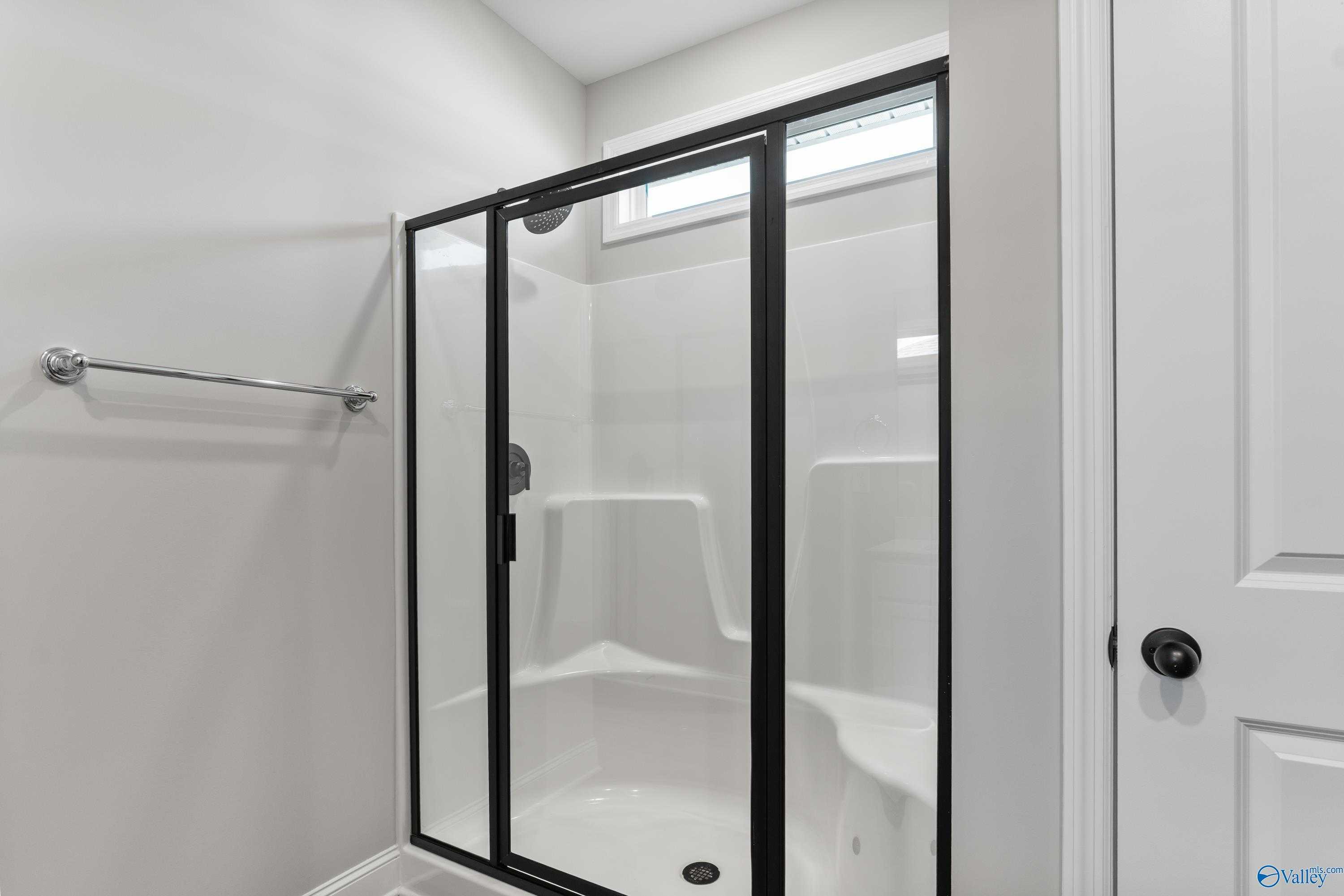 Modern frameless glass shower with corner bench and window in master bath of Davidson Homes The Franklin B, Hazel Green, AL