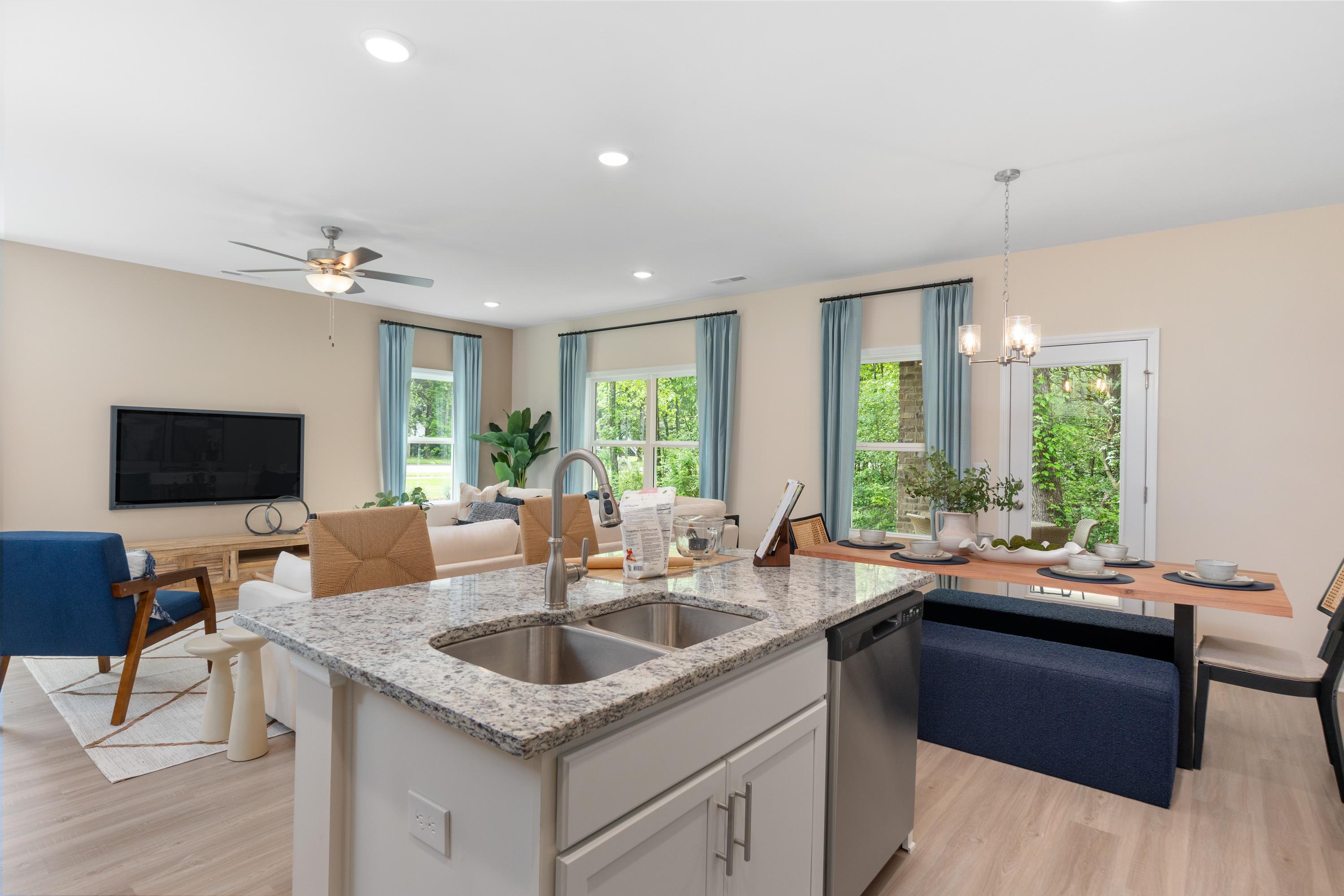 Open-concept kitchen and living area at Pavilion in Huntsville AL with granite island, hardwood floors, large windows