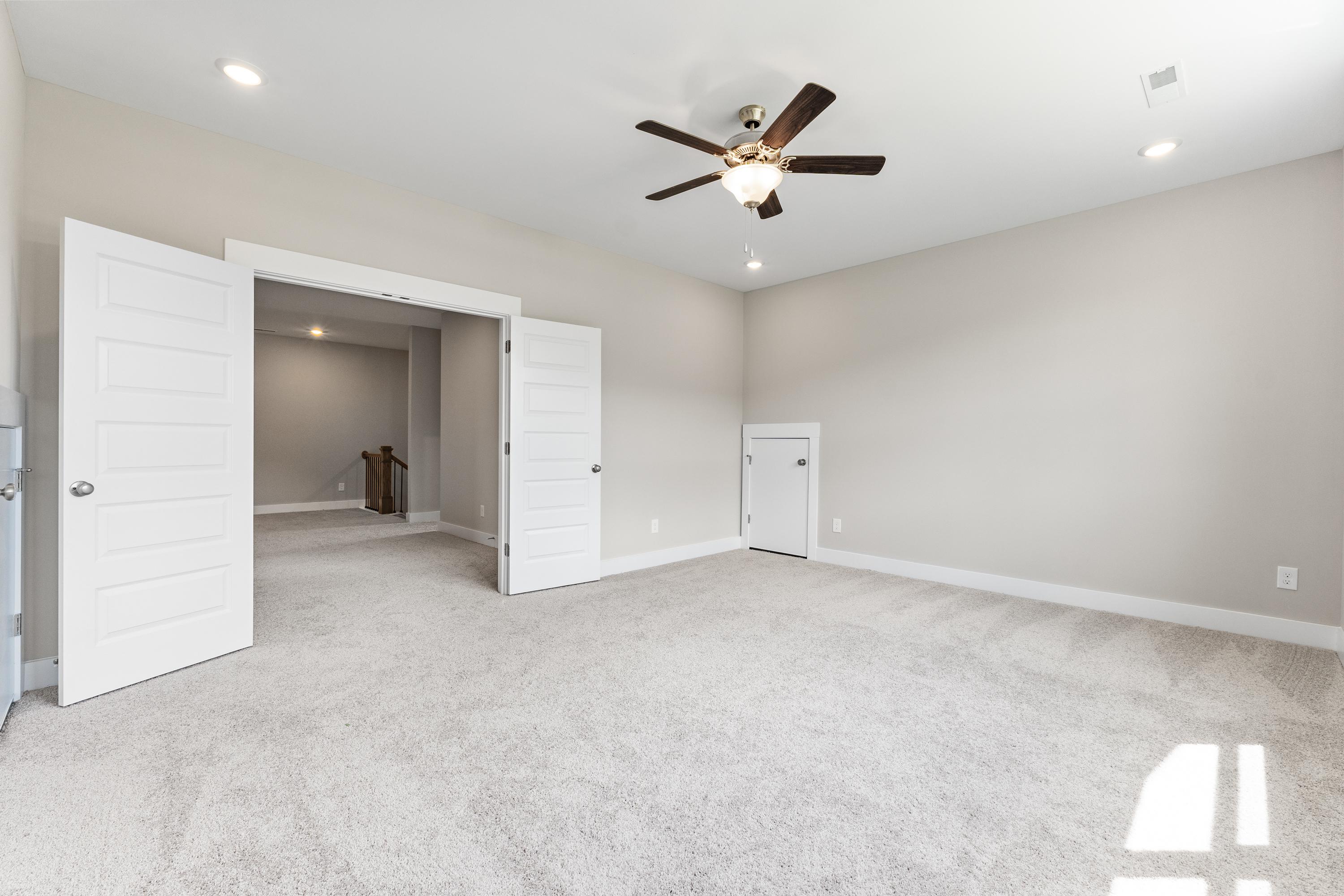 Spacious entryway in The Oxford A home with open double doors, beige carpeted floor, ceiling fan, and neutral walls