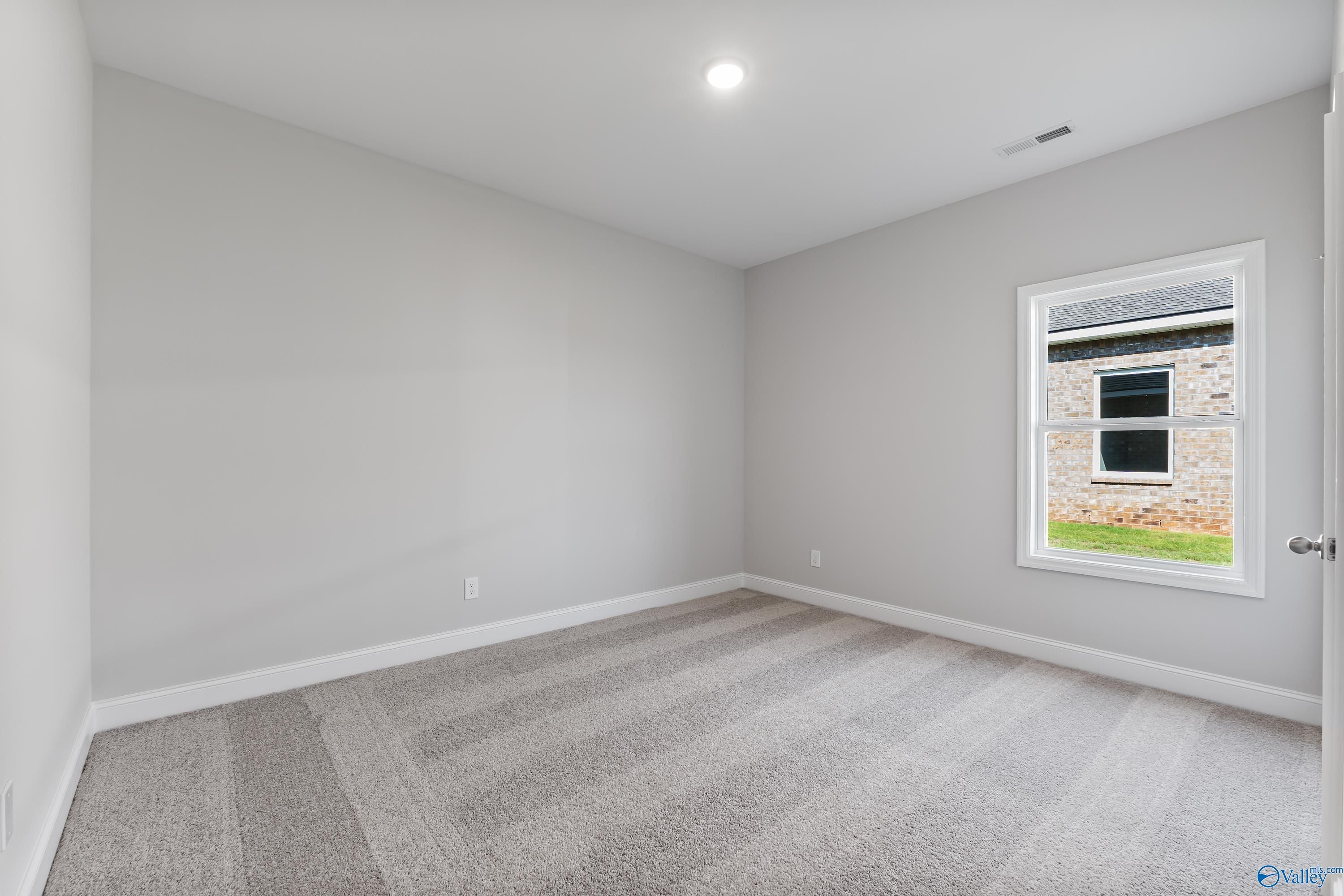 Neutral gray bedroom with plush carpet, large window view, and recessed lighting in Davidson Homes The Daphne, Hazel Green, Alabama