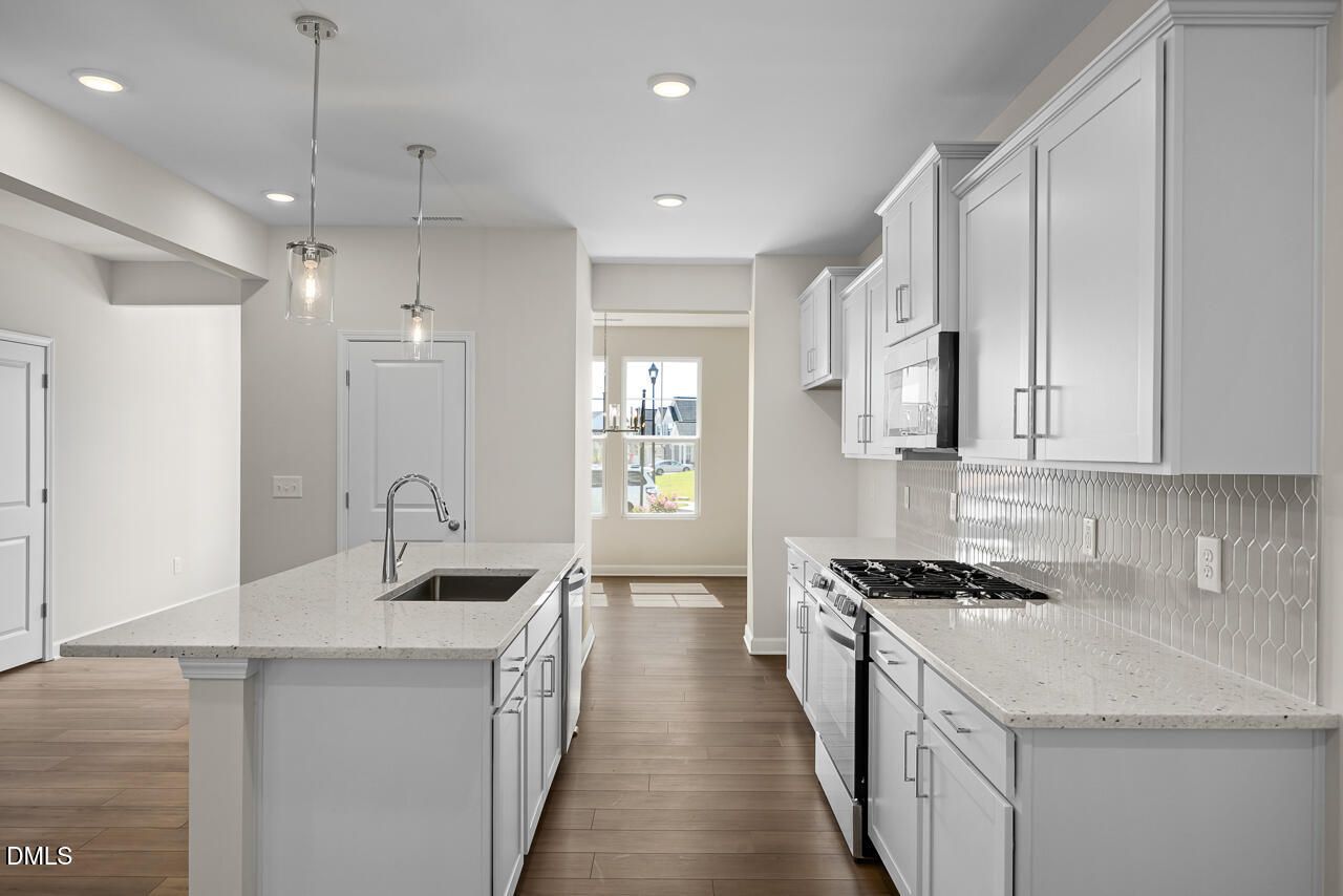 Modern kitchen with white cabinetry, quartz countertops, and gas range in Davidson Homes Willow C plan, Zebulon, NC