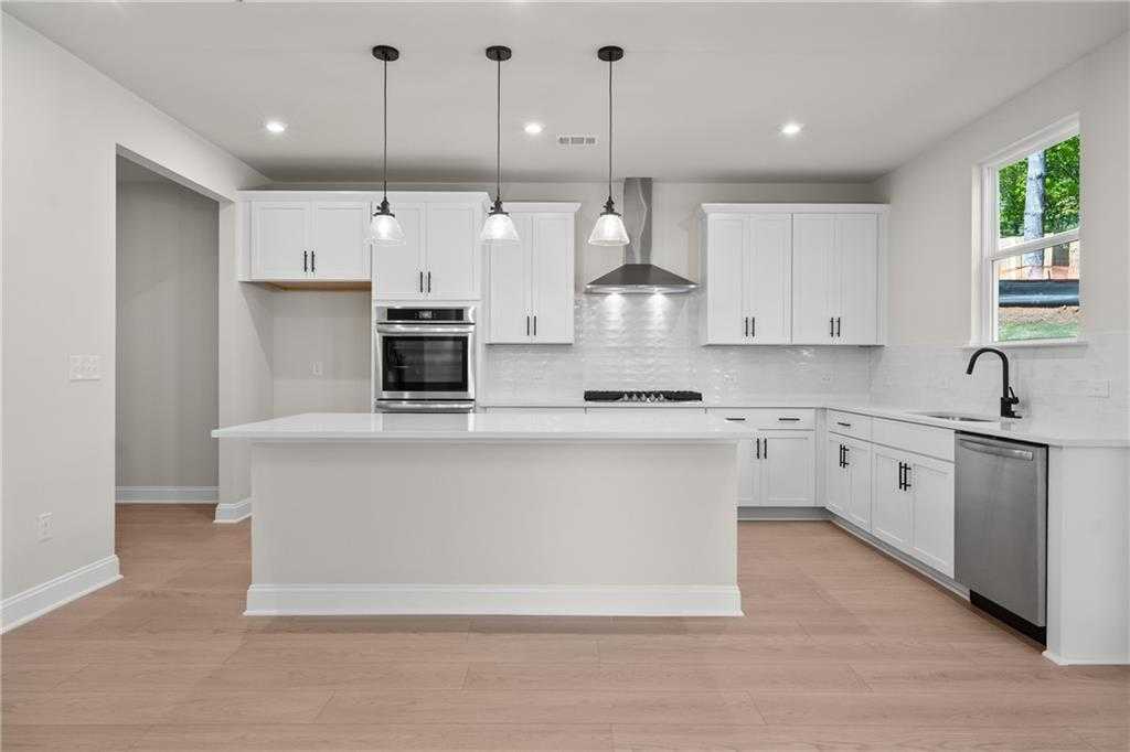 Modern white kitchen with large island, stainless appliances, subway tile backsplash in Davidson Homes The Hickory E, Buford, GA