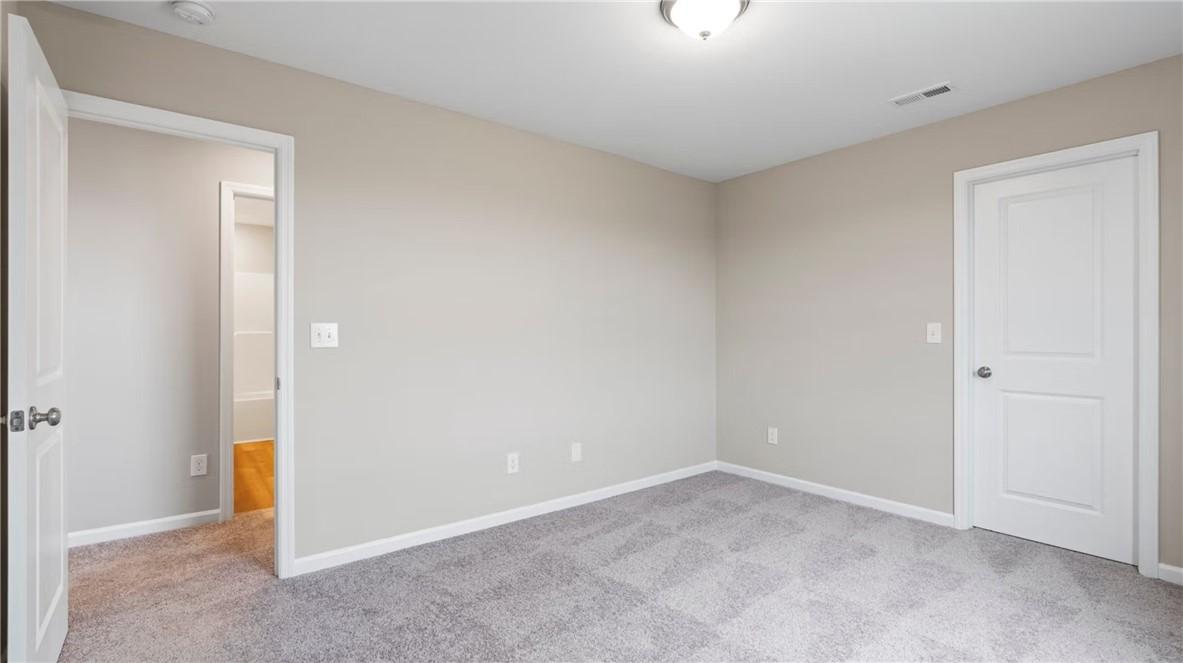 Spacious secondary bedroom with beige walls, carpet floor, attached bath, and closet in Evermore Homes The Stella D, Cusseta, Alabama