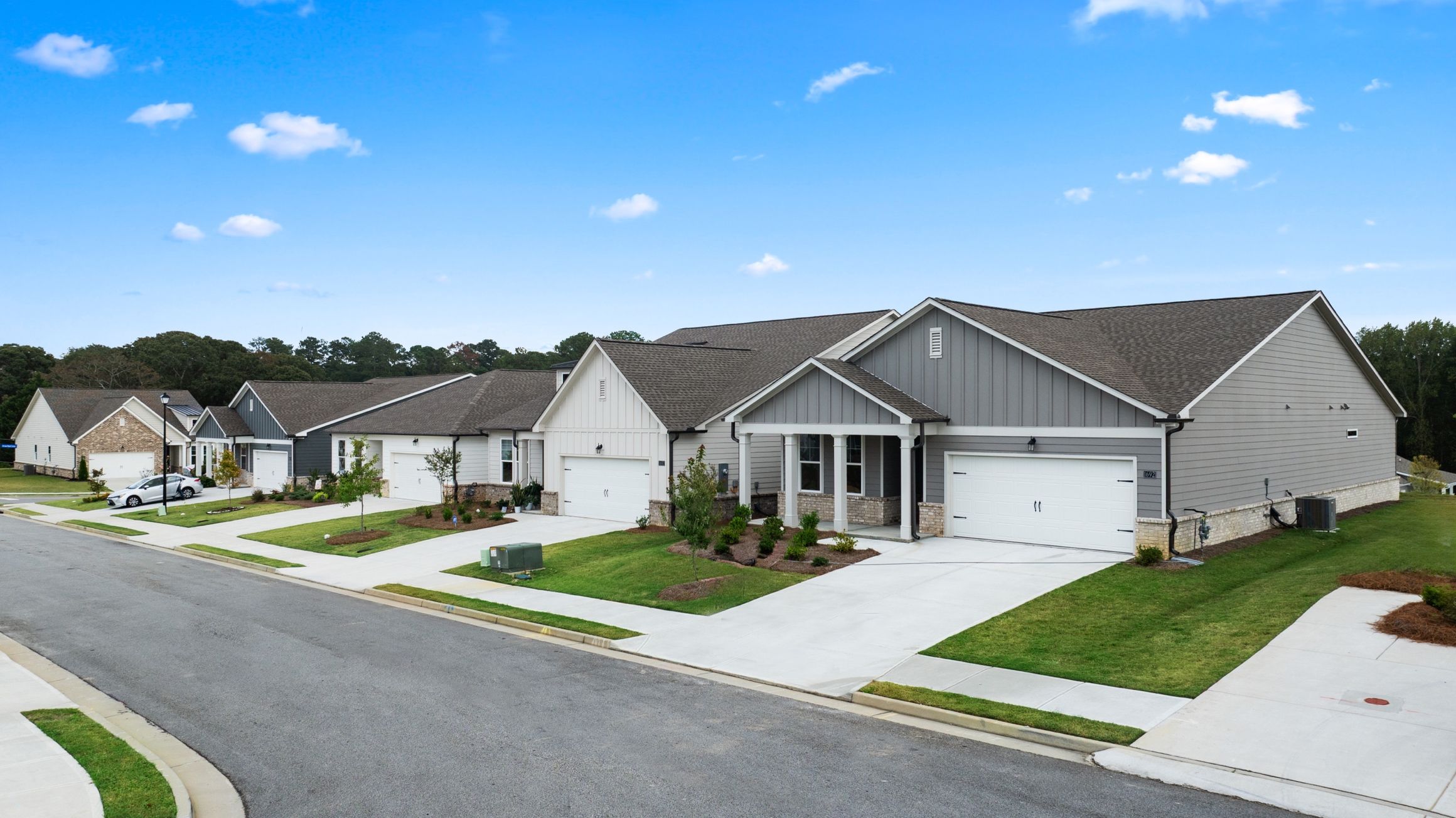 Row of modern gray homes with garages, porches and manicured lawns at Kelly Preserve in Loganville GA by Davidson Homes