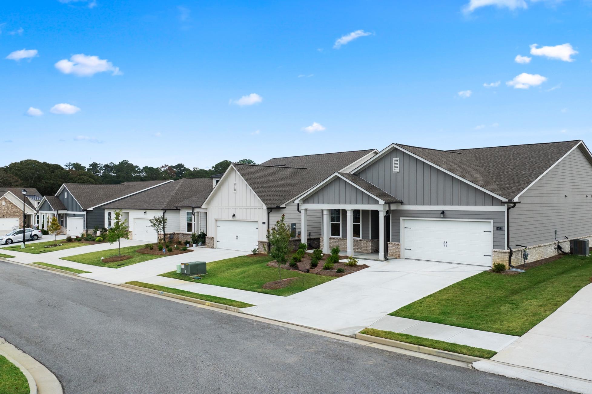 Row of modern gray homes with garages, porches and manicured lawns at Kelly Preserve in Loganville GA by Davidson Homes