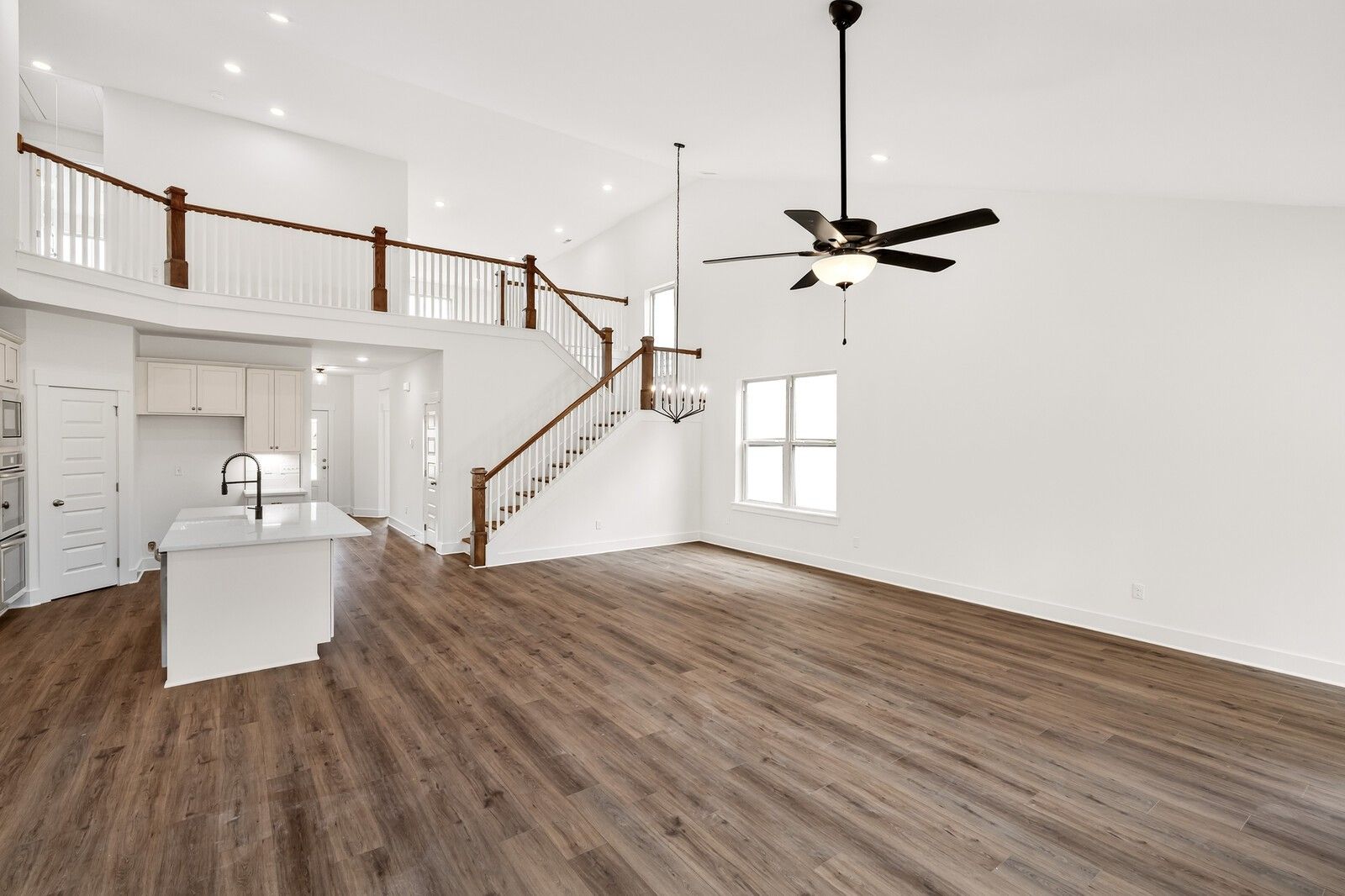 Spacious open kitchen with white island, hardwood floors, wooden staircase to balcony in Davidson Homes Ridgeport C, Gallatin TN