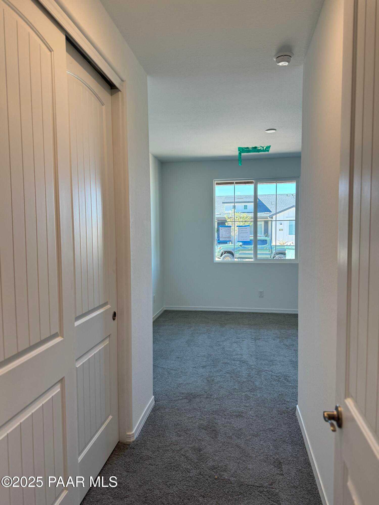 Bright hallway with gray carpet, paneled doors, and window view in Davidson Homes The Sunrise II A, Prescott AZ