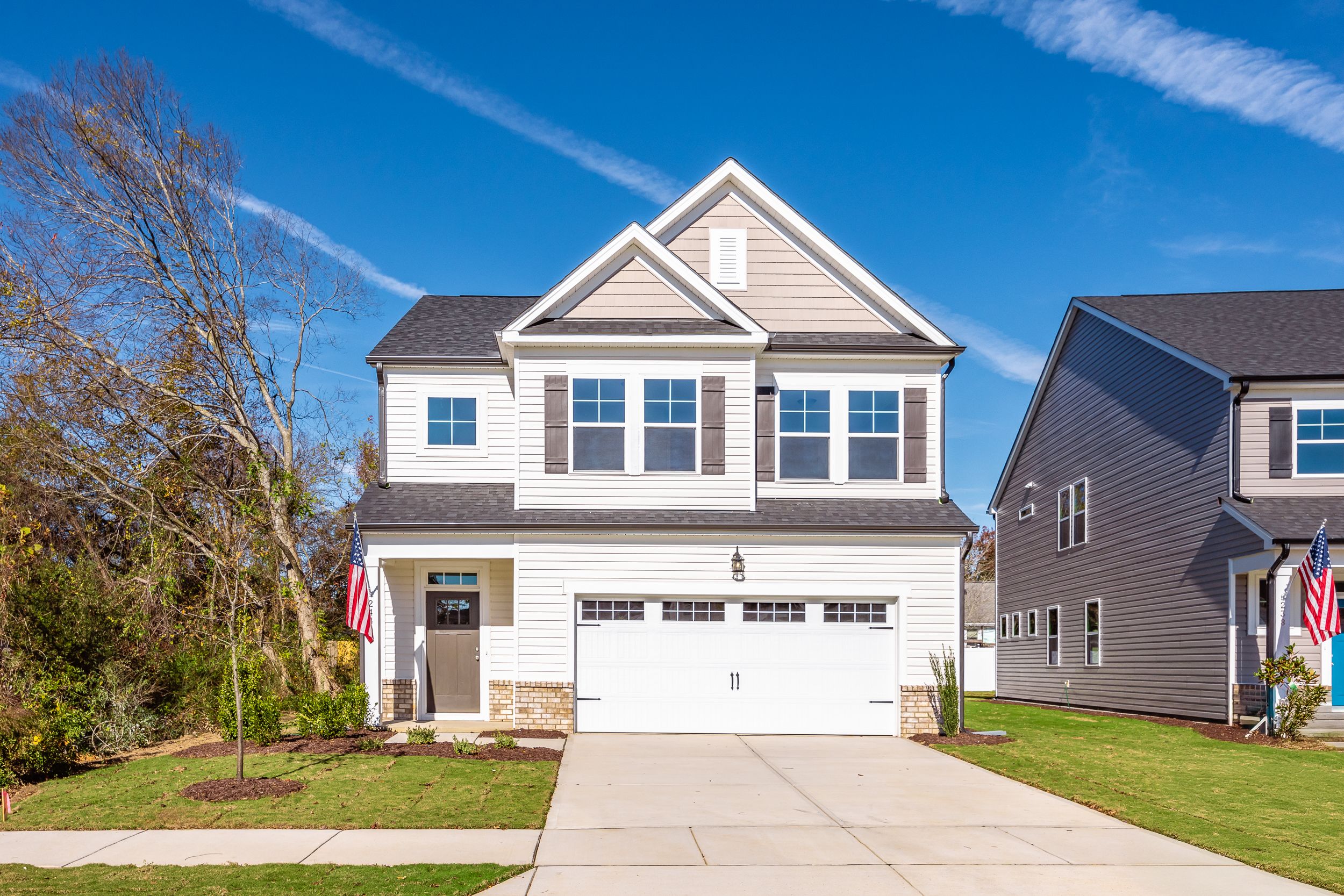 Two-story craftsman home exterior at Gregory Village in Lillington NC with attached garage, gabled roof, and American flag
