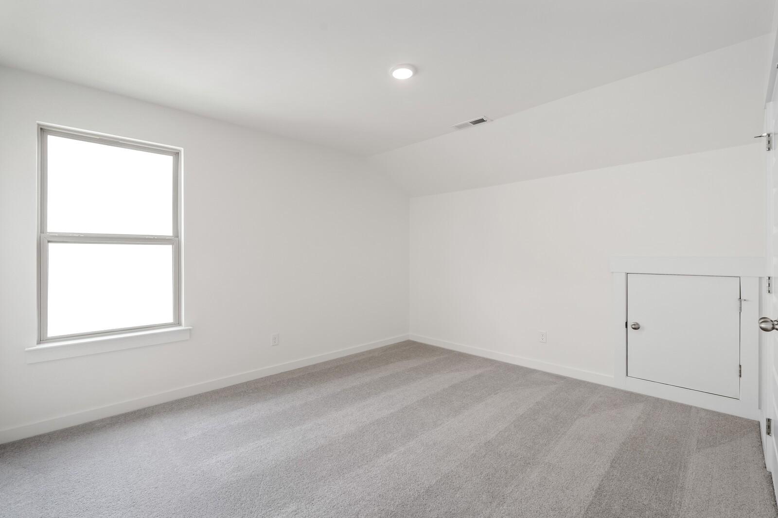 Bright bedroom with carpet and attic access in The Ridgeport C floor plan at Woods Crossing in Gallatin, TN.
