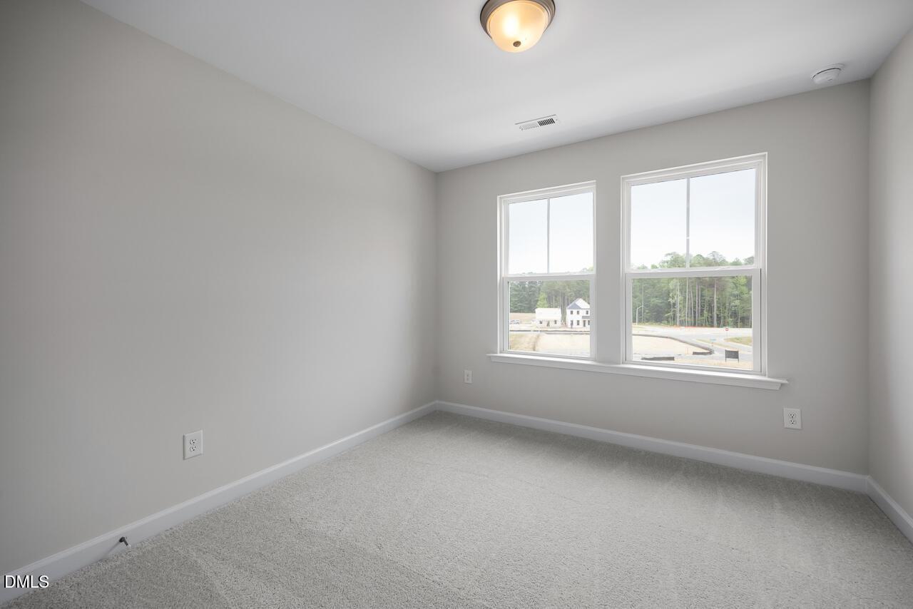 Bright bedroom with neutral carpet and large windows in The Mitchell Interior floor plan at Forestville Yard, Knightdale.