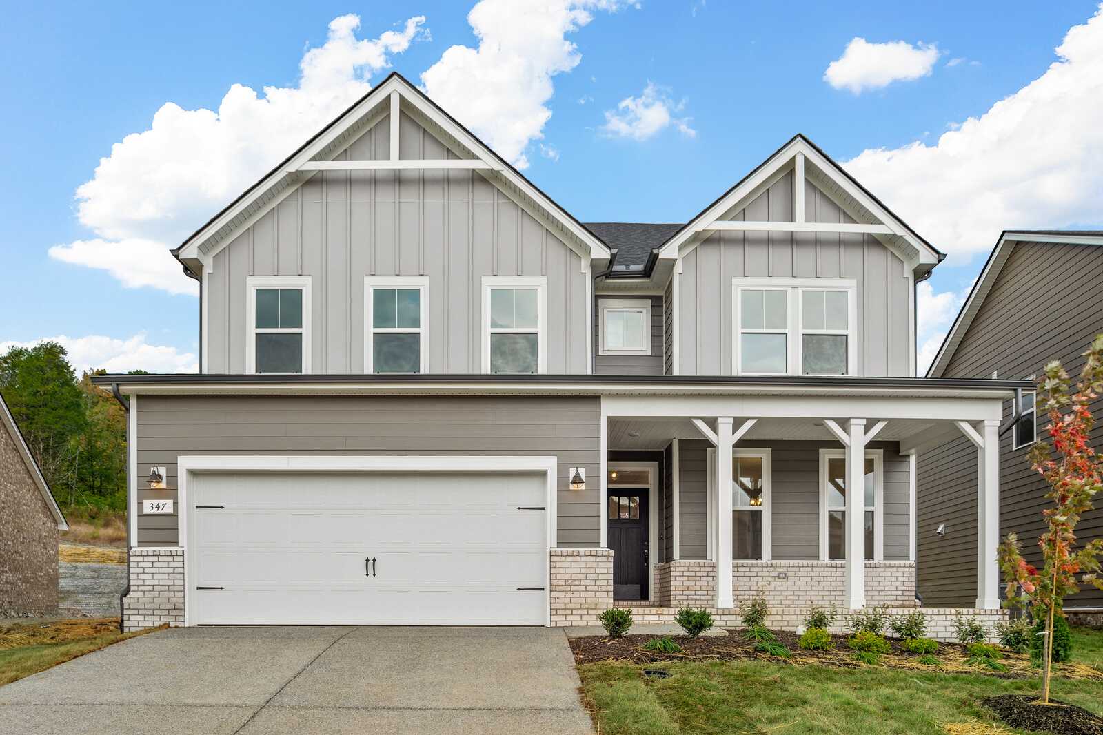 Two-story gray Craftsman-style home with covered front porch and garage at Woods Crossing in Gallatin, Tennessee