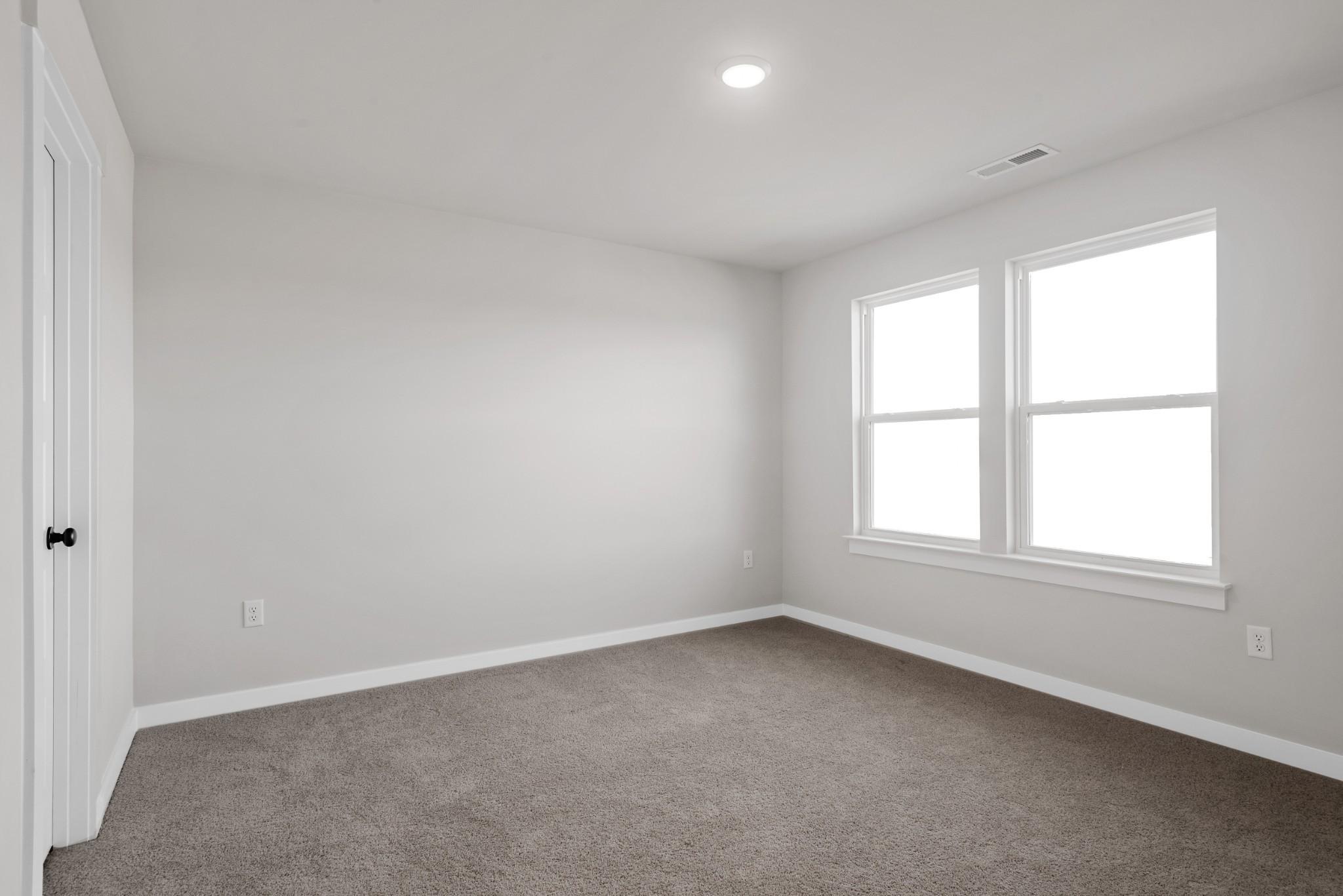 Bright secondary bedroom with light gray walls, neutral carpet, large double windows in Davidson Homes The Willow B, Calista Farms, White House, TN