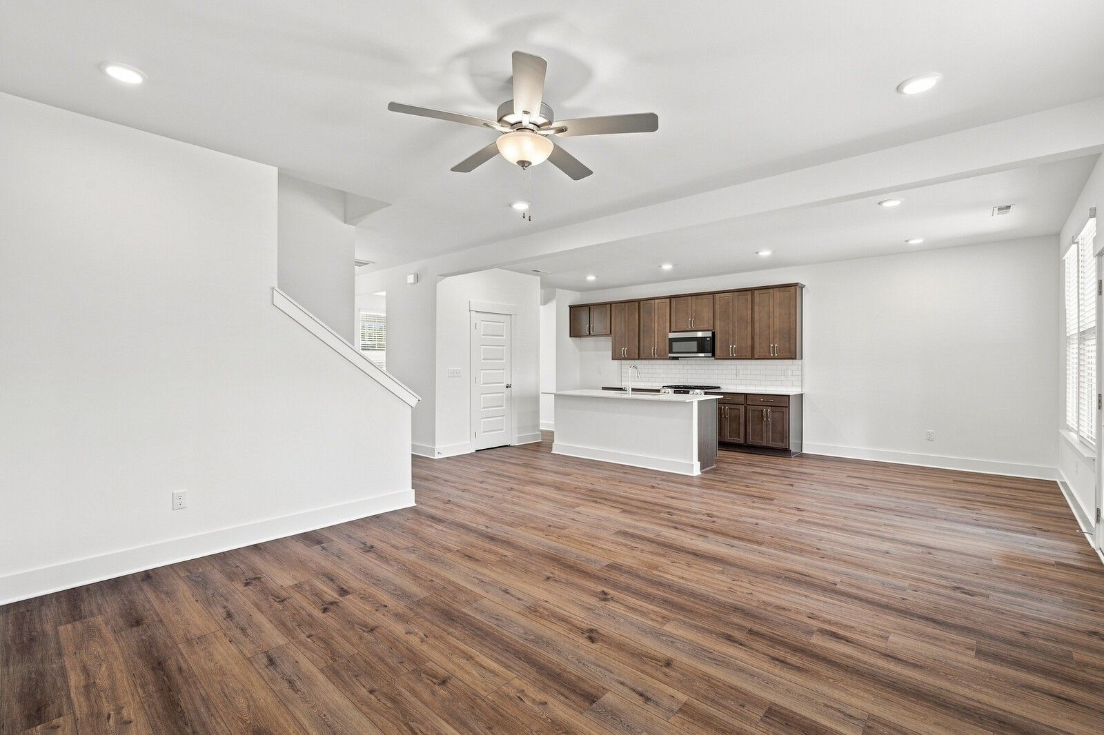 Open-concept living area with luxury vinyl plank flooring, ceiling fan, and kitchen with espresso cabinets in The Willow C, Gallatin TN