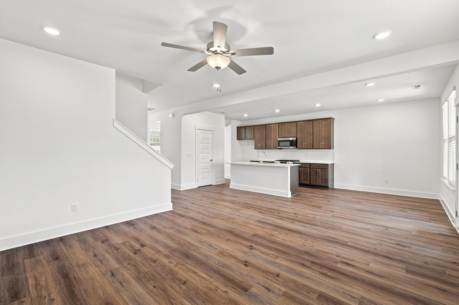 Open-concept living area with luxury vinyl plank flooring, ceiling fan, and kitchen with espresso cabinets in The Willow C, Gallatin TN