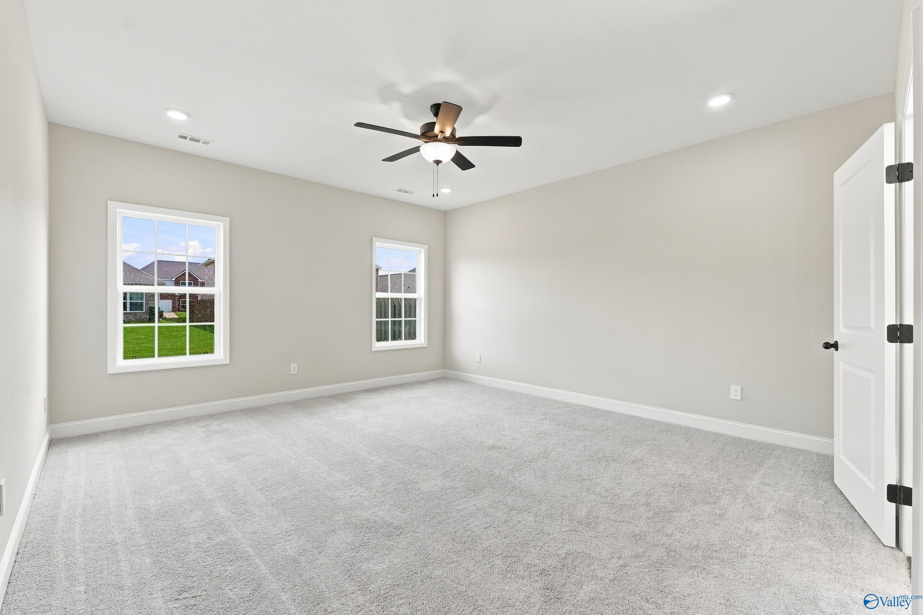 Spacious carpeted bedroom with ceiling fan in The Rockford B floor plan at Kendall Downs, Toney, Alabama.