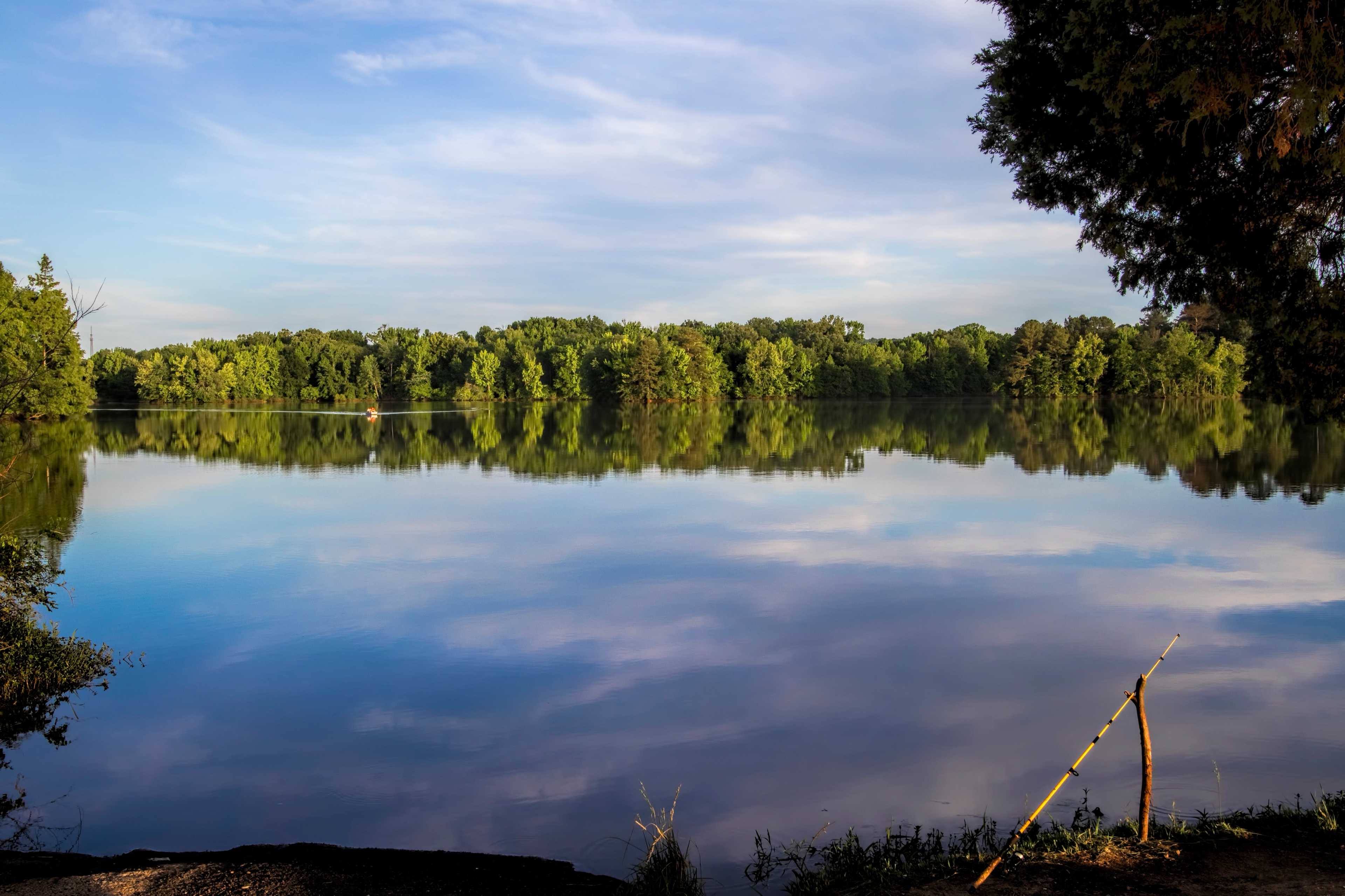 Serene lake with lush tree reflections and calm blue waters at Little Creek in Arab, Alabama