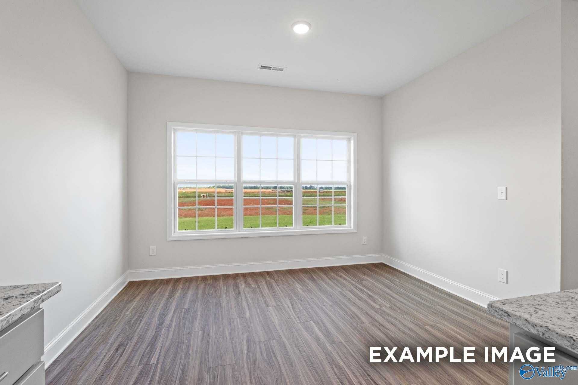 Bright living room with large windows overlooking green fields in The Montgomery 3-bedroom home, Davidson Homes, Athens, Alabama