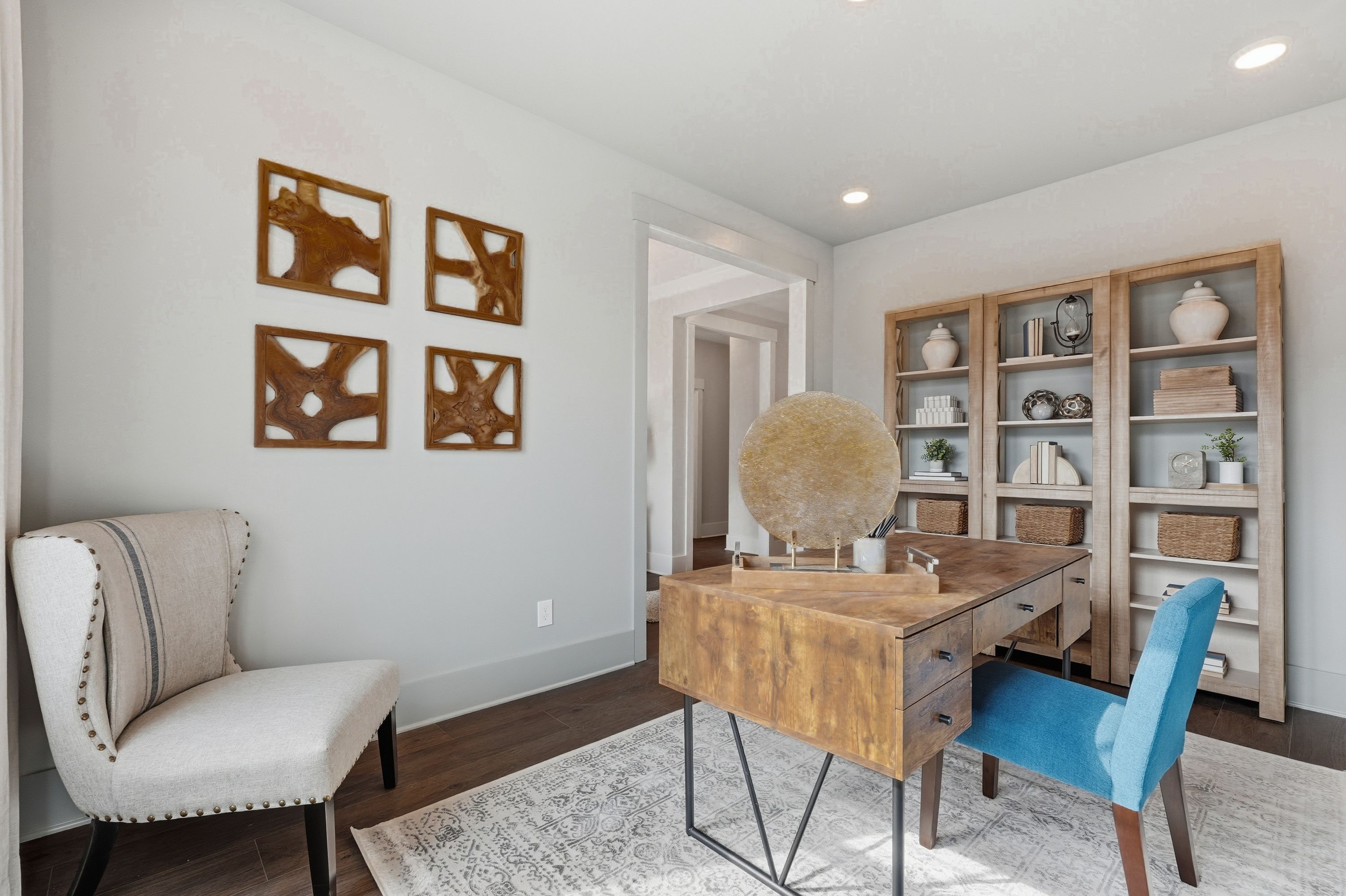 Cozy home office in Noble Ridge Cullman Alabama with wooden desk, blue accent chair, bookshelves, and abstract art