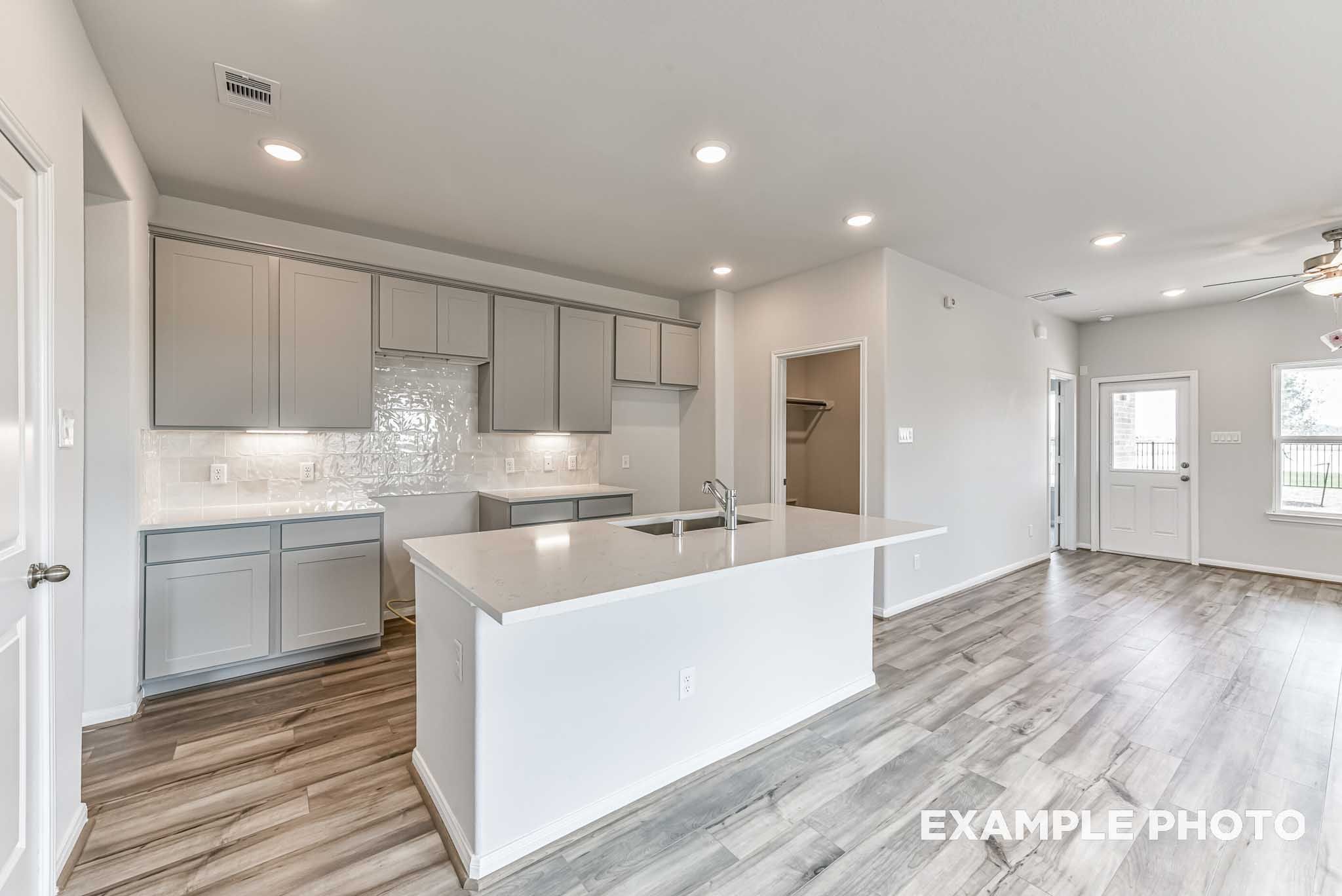 Open-concept kitchen in The Azure by Davidson Homes featuring large island, gray cabinetry, and luxury vinyl plank flooring