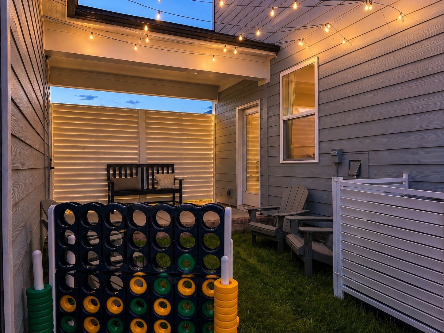 Cozy outdoor patio of The Burke C in Knightdale featuring string lights, a bench, yard games, and a private backyard space.