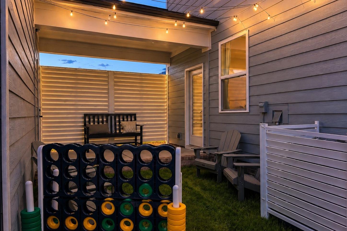 Cozy outdoor patio of The Burke C in Knightdale featuring string lights, a bench, yard games, and a private backyard space.