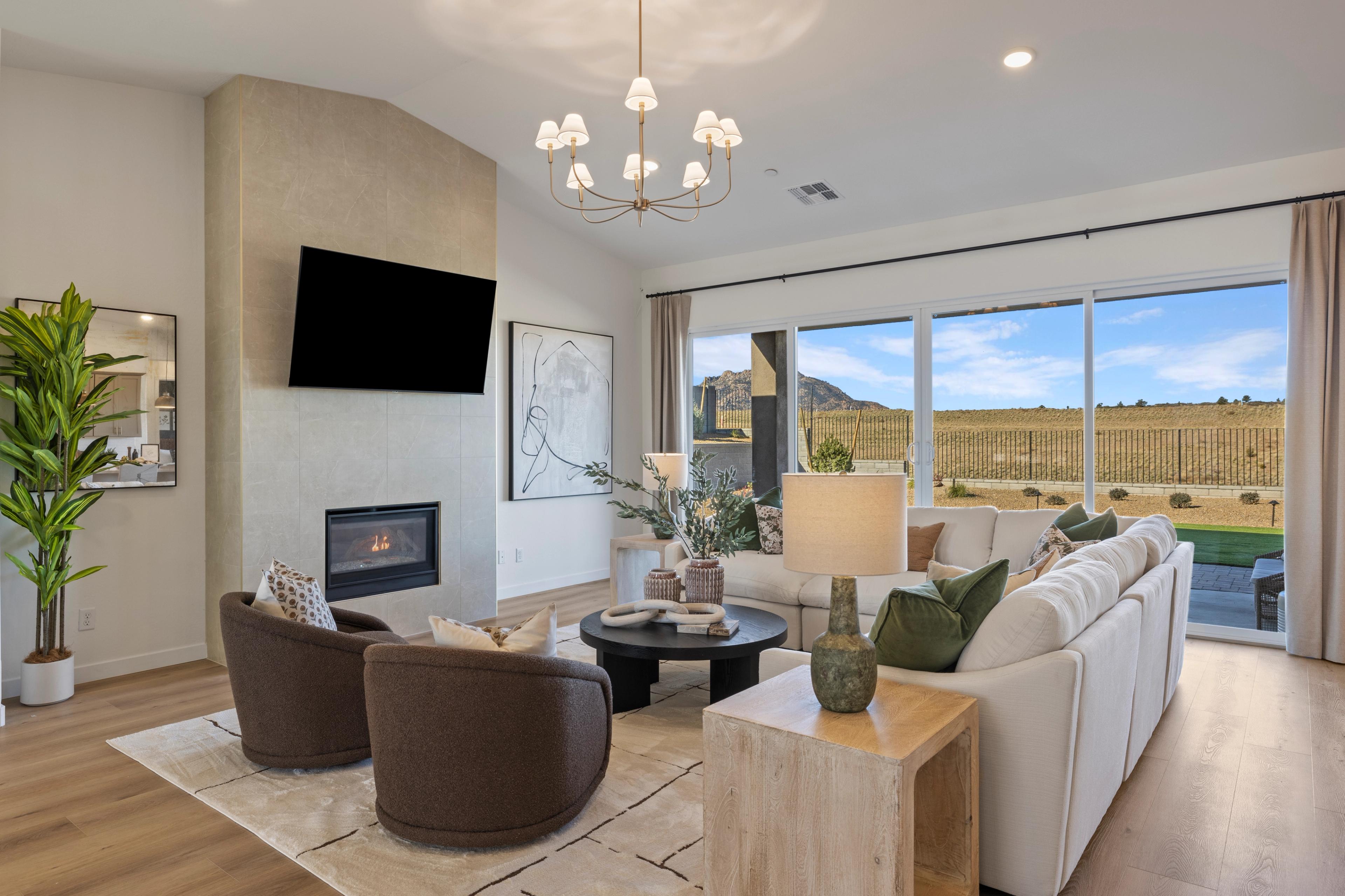 Cozy living room in Hidden Hills Prescott AZ by Davidson Homes with stone fireplace, modern seating, chandelier, and mountain views through sliding doors